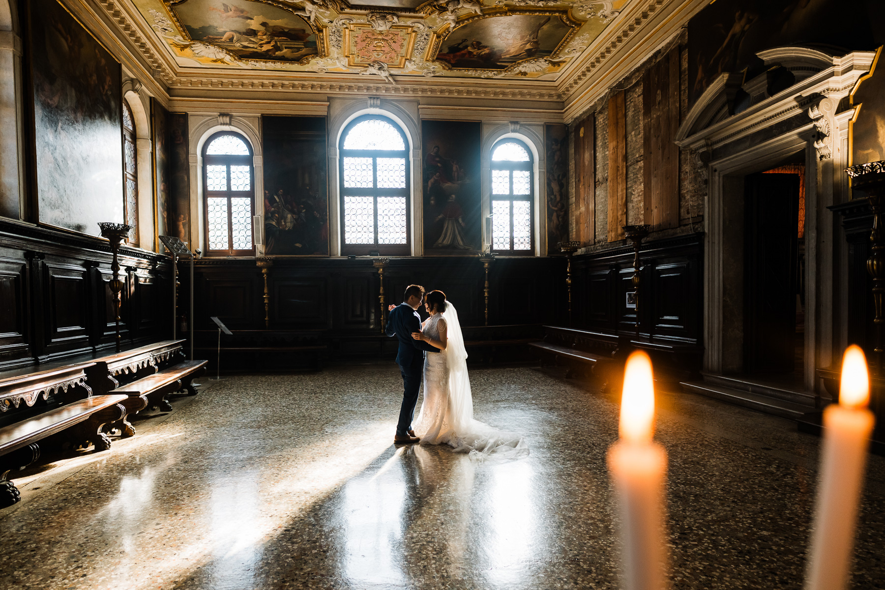 Couple standing in the ornate interior of Scuola Grande dei Carmini in Venice.