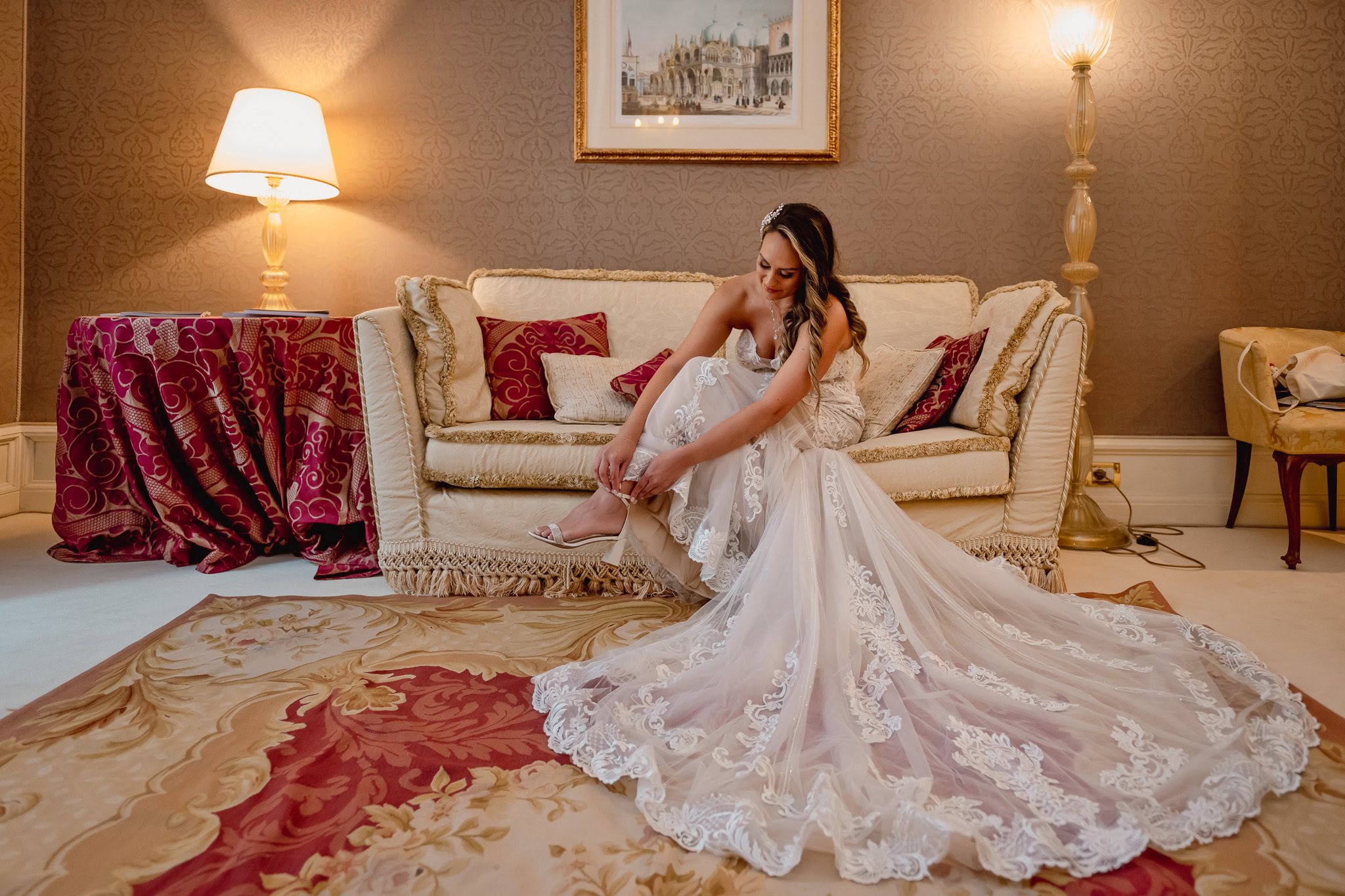 A woman in a wedding dress sitting on a sofa inside a Venetian palace.