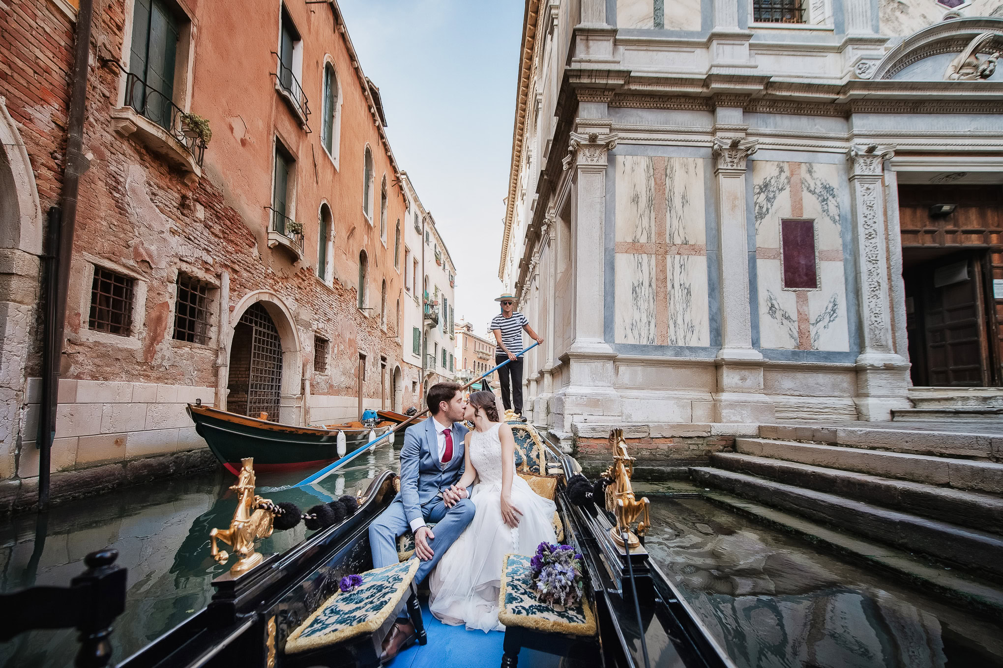A beautiful intimate couple sharing a tender moment on a gondola amidst the historic canals of Venice.
