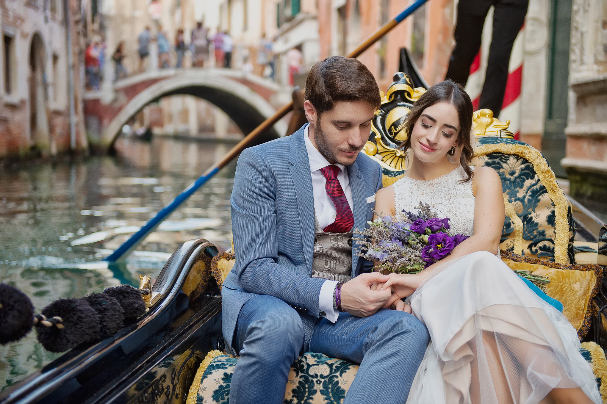 Intimate couple sharing a tender moment on a gondola in Venice, illuminated by soft natural light.