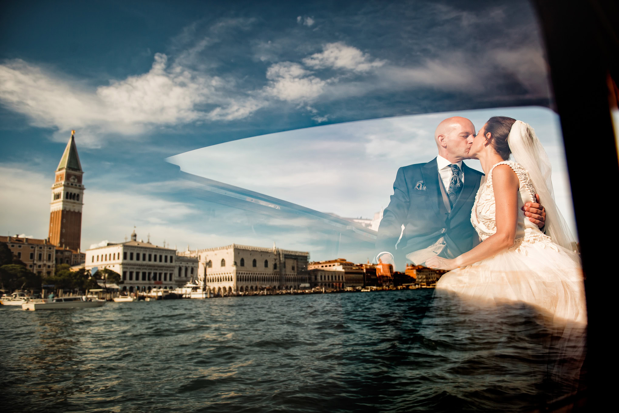 A couple sharing an intimate moment with Venice's skyline and water reflections creating a romantic atmosphere.