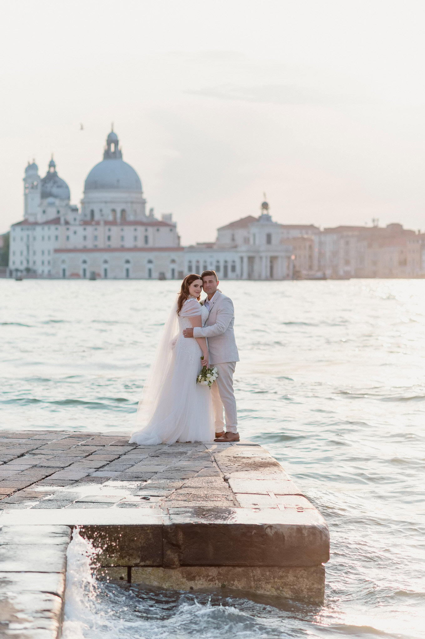 A couple sharing an intimate moment on a Venetian dock at sunset, with soft light illuminating their connection.