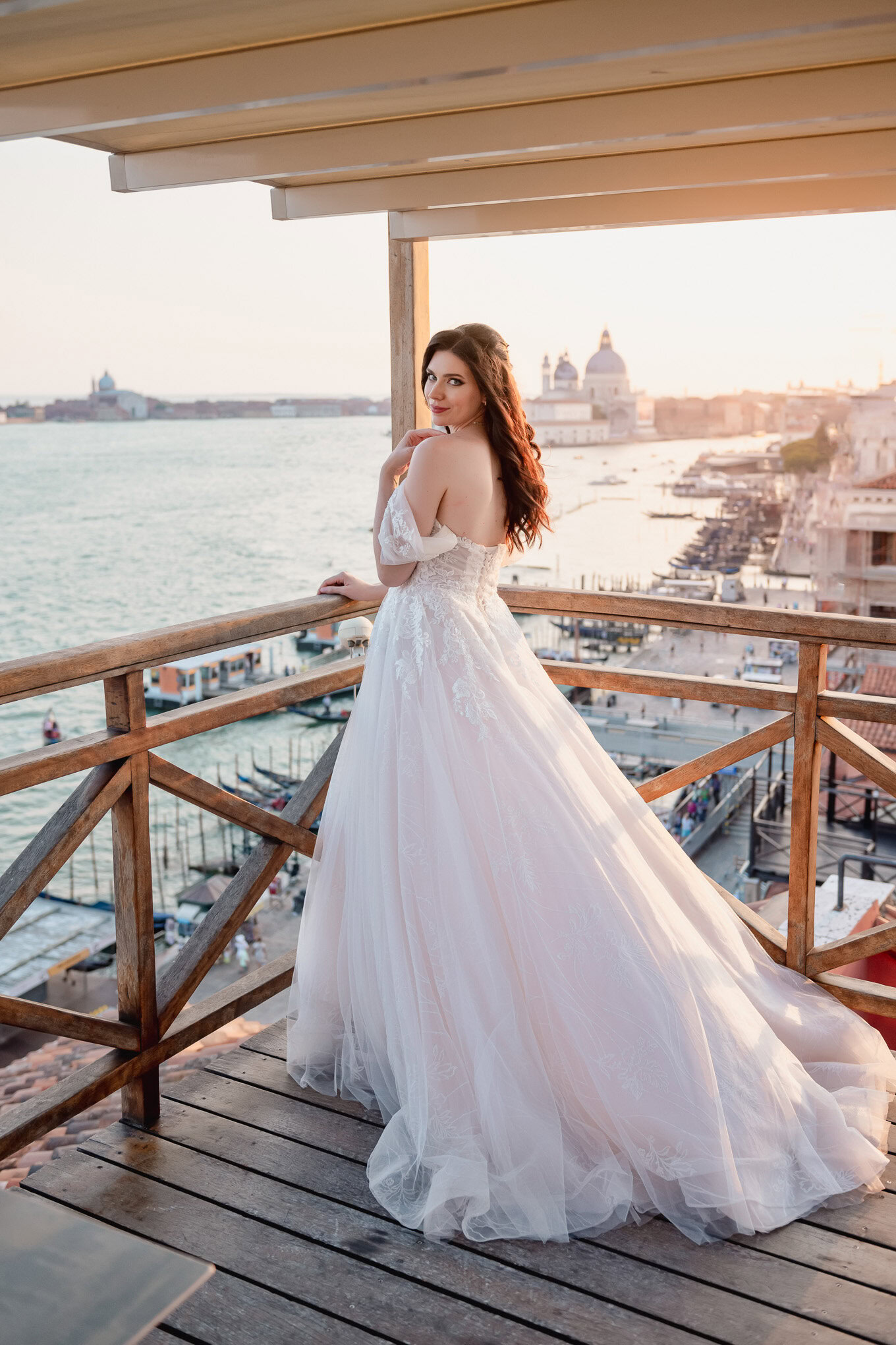 A beautiful intimate couple on a Venetian balcony at sunset, with warm light illuminating their quiet moment overlooking.