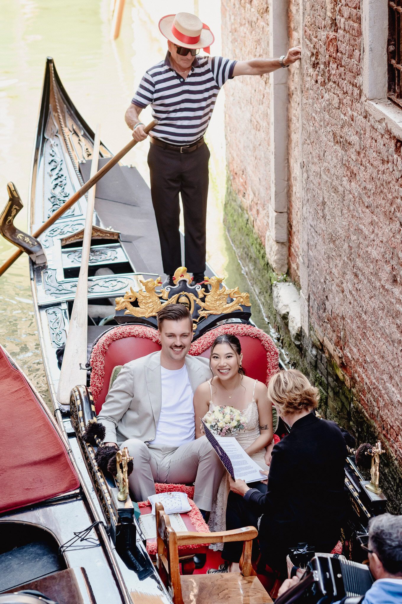 An intimate couple sharing a moment on a gondola in Venice, bathed in soft natural light, with historic brick walls.