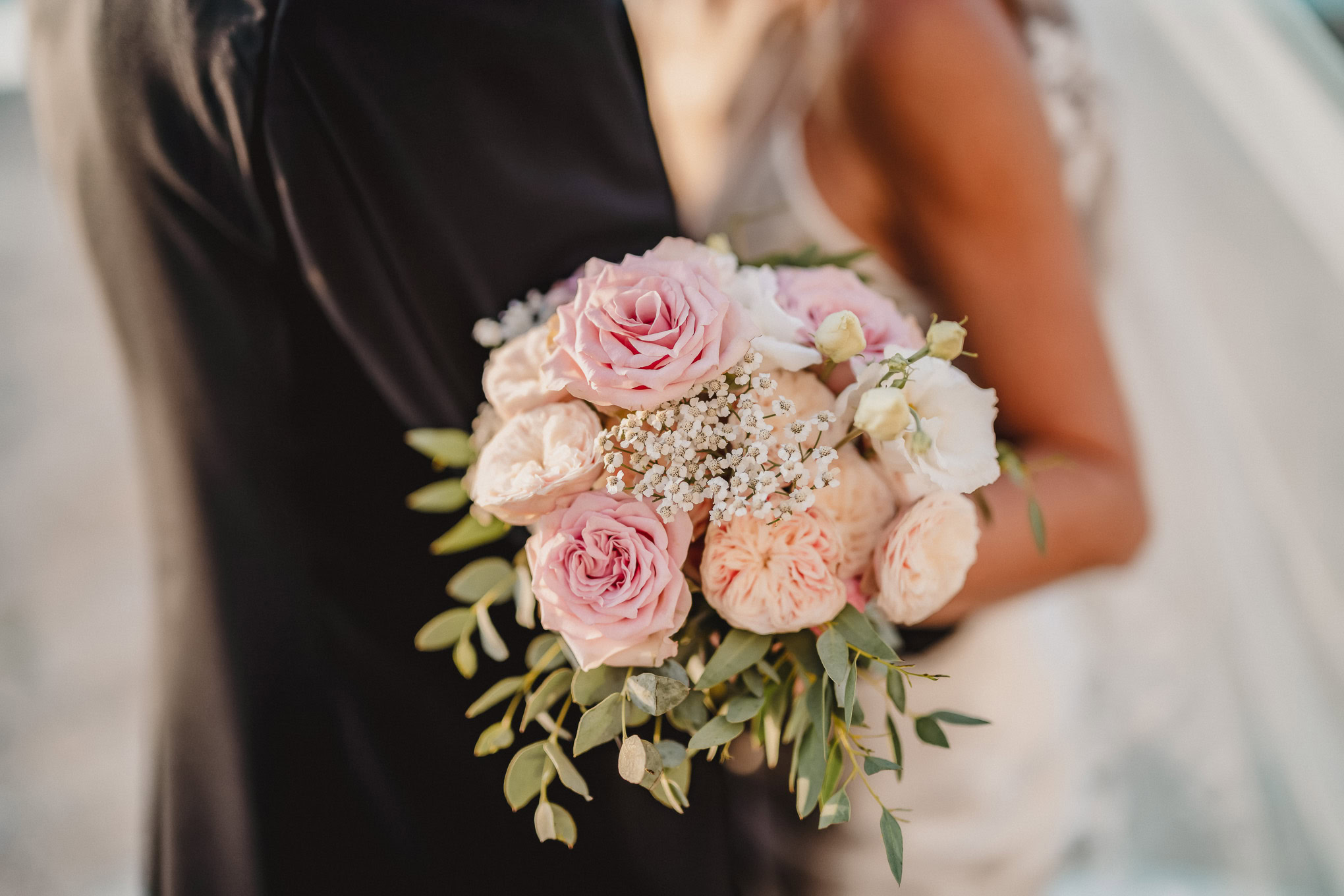 Intimate couple holding a romantic bouquet in Venice with soft natural light and atmospheric surroundings.