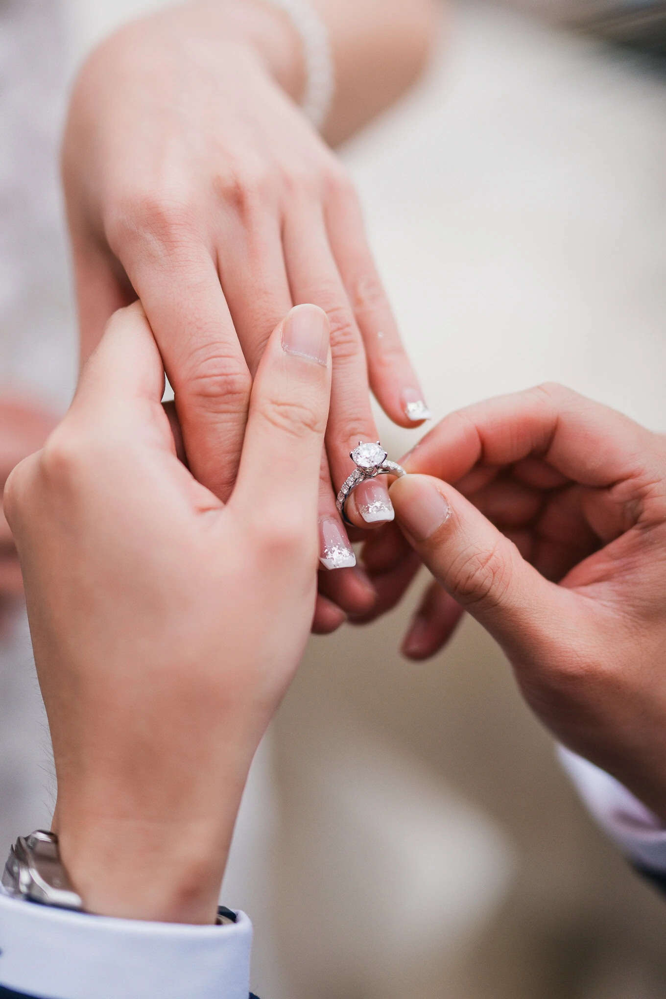 A woman’s hand gently receives a ring from another person, illuminated by soft, natural light, evoki.
