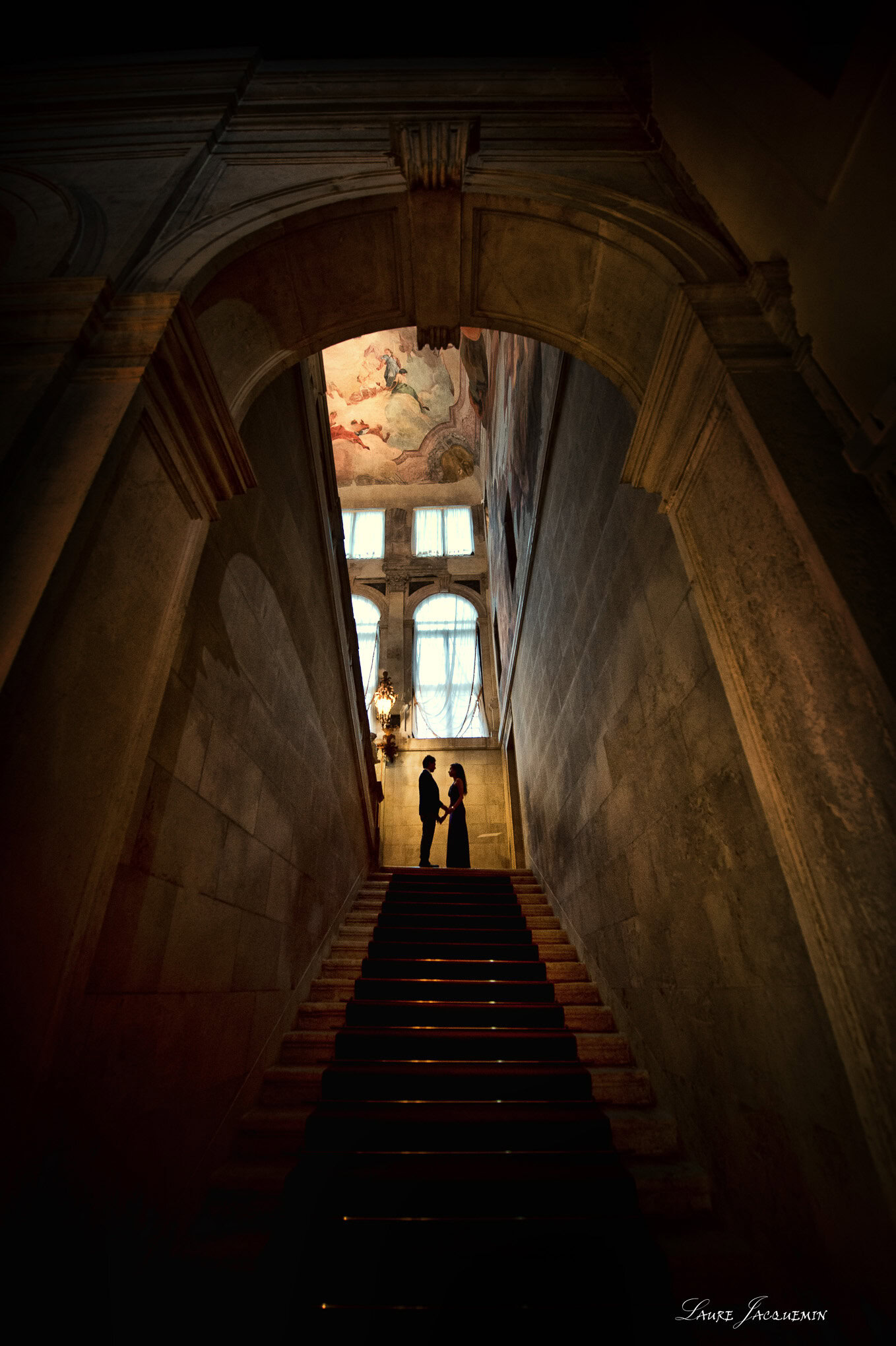 A serene moment of two figures silhouetted against a luminous window at the top of a grand staircase.