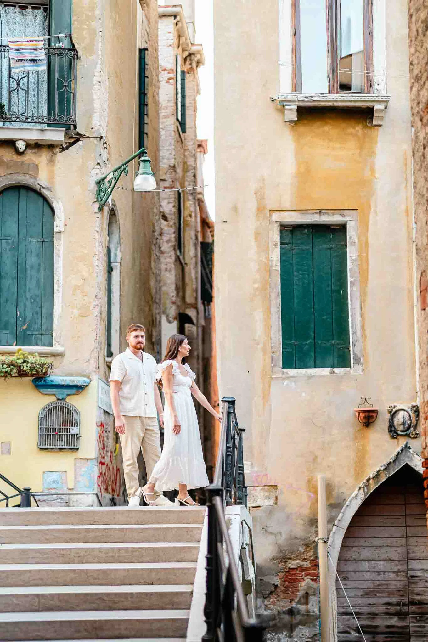 A couple walking hand in hand along a narrow, sunlit alleyway with weathered, colorful buildings cre.