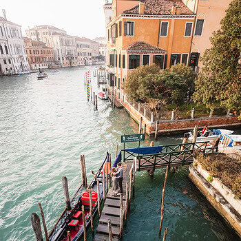A serene scene of gondolas docked along a quiet canal in Venice, bathed in warm, soft light with his.