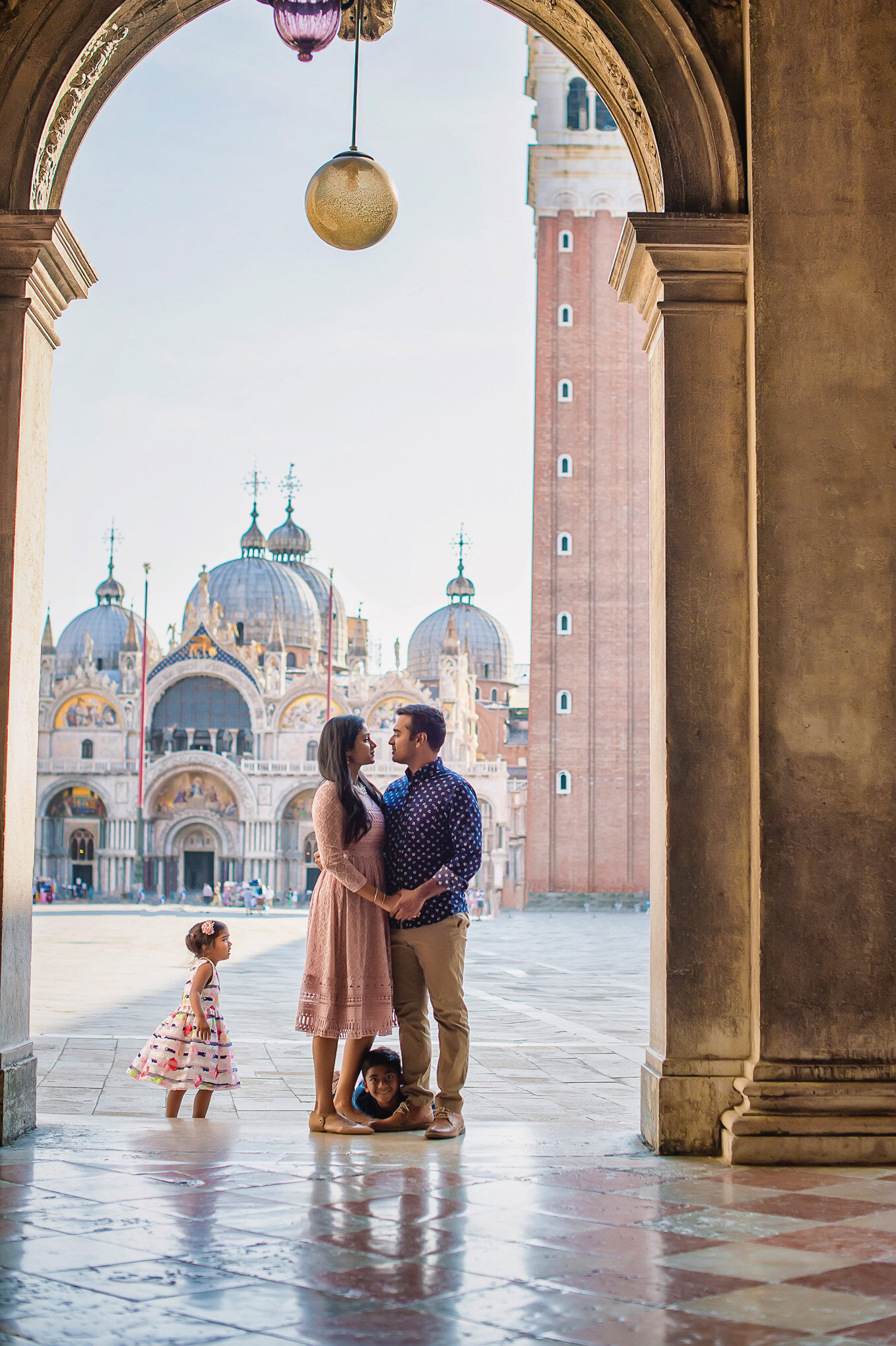 A colorful family moment captured under an archway with historic Venice architecture and soft natural light illuminating.