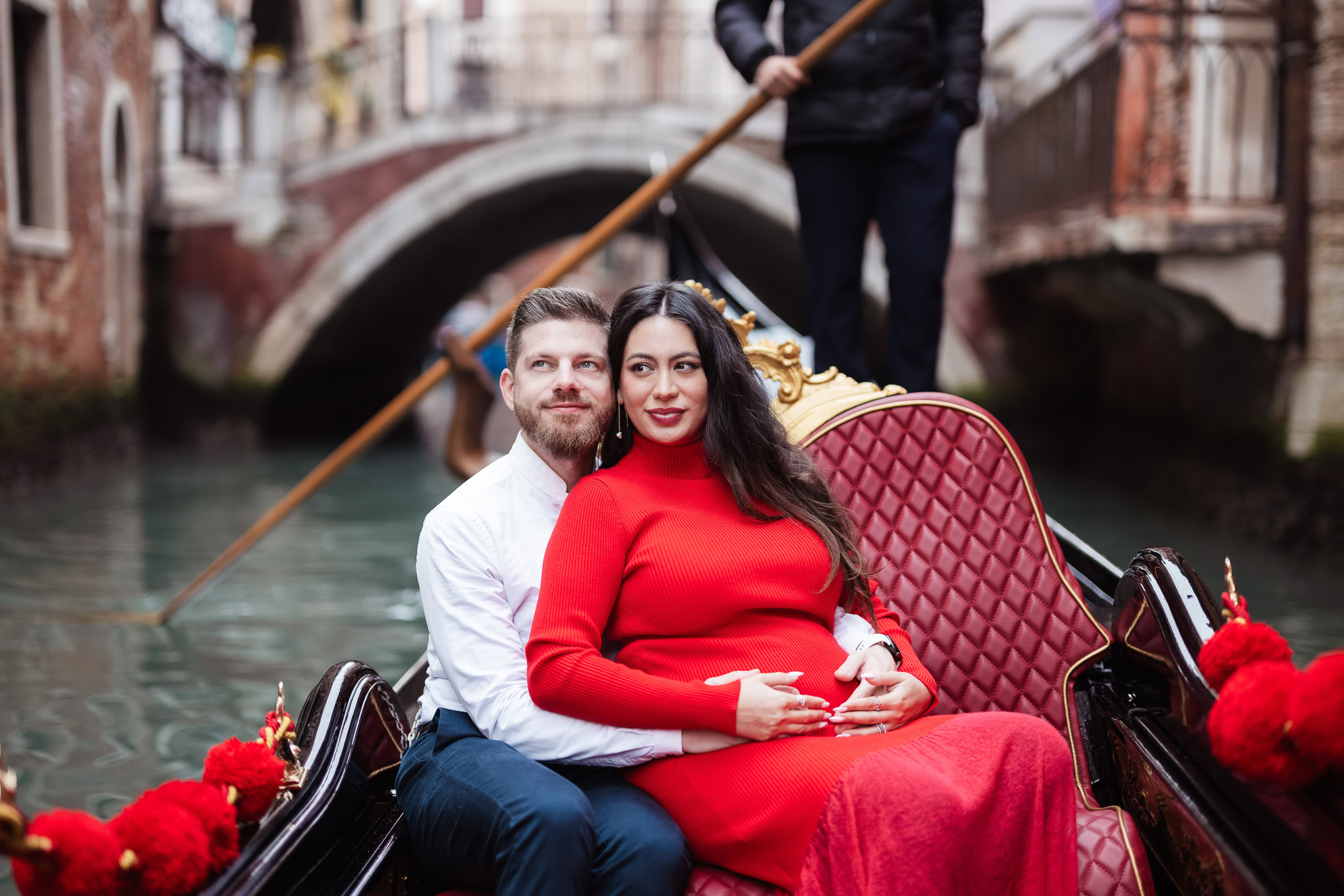 Romantic couple on a gondola in Venice with historic buildings and a canal in the background.