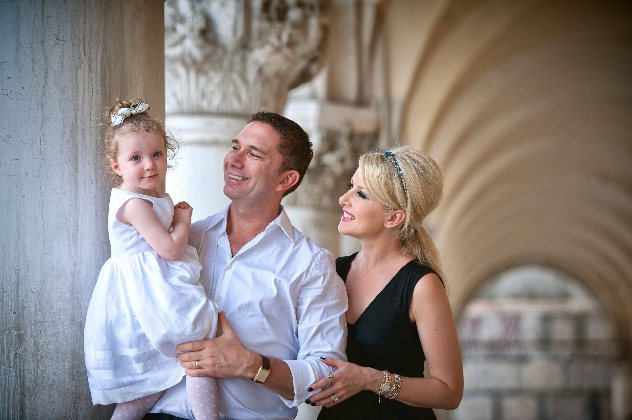 Family enjoying a joyful moment together under Venice’s historic arches in soft natural light.