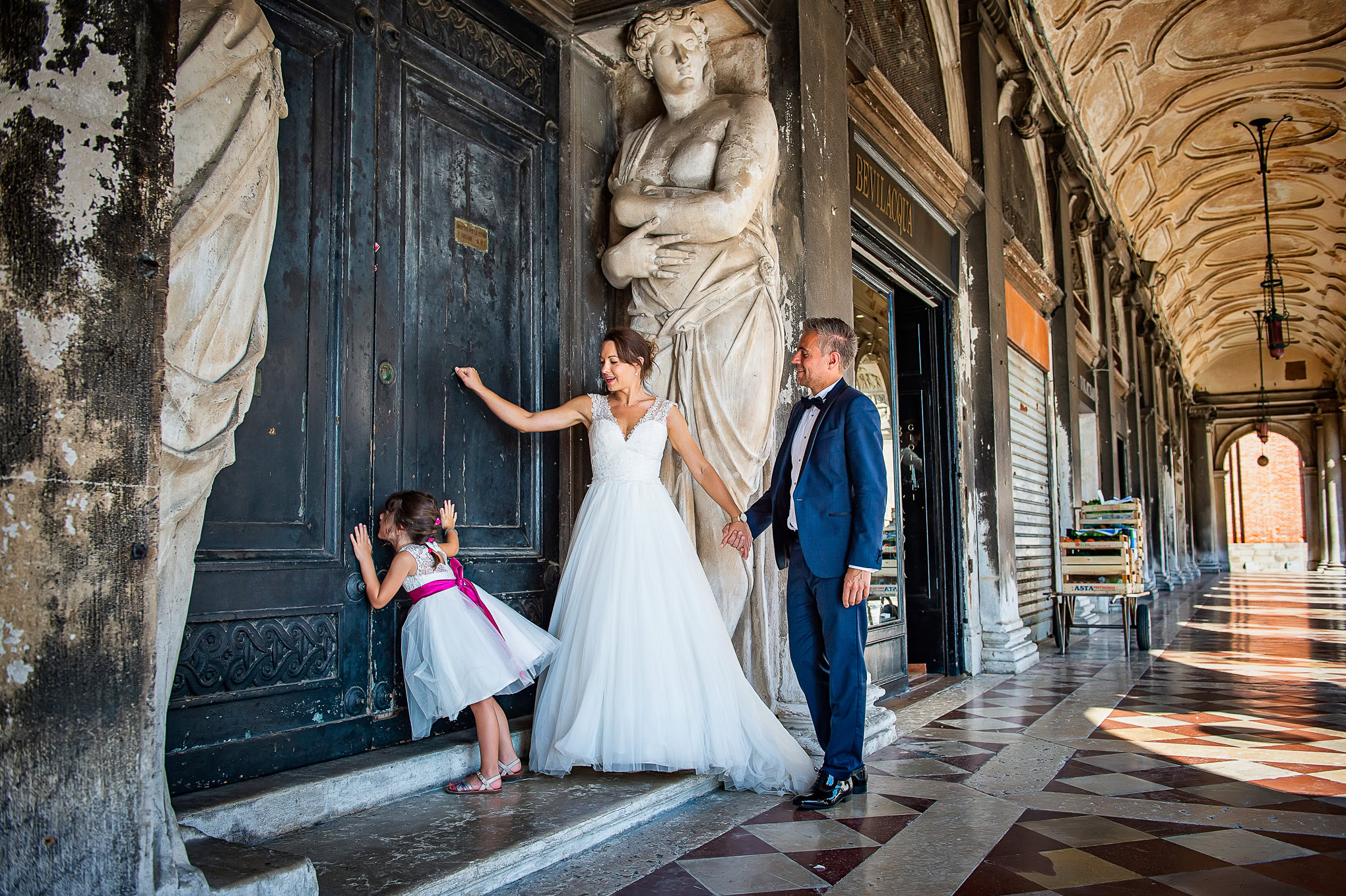 A woman and a man with a young girl explore a historic Venetian building, engaging with the ornate door and enjoying a s.