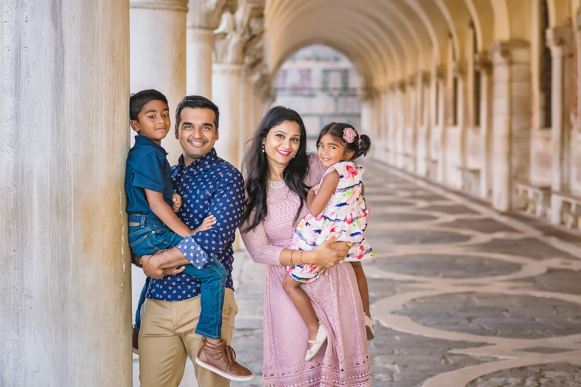 A detailed family moment in Venice with children and parents enjoying a sunny day under historic arches.