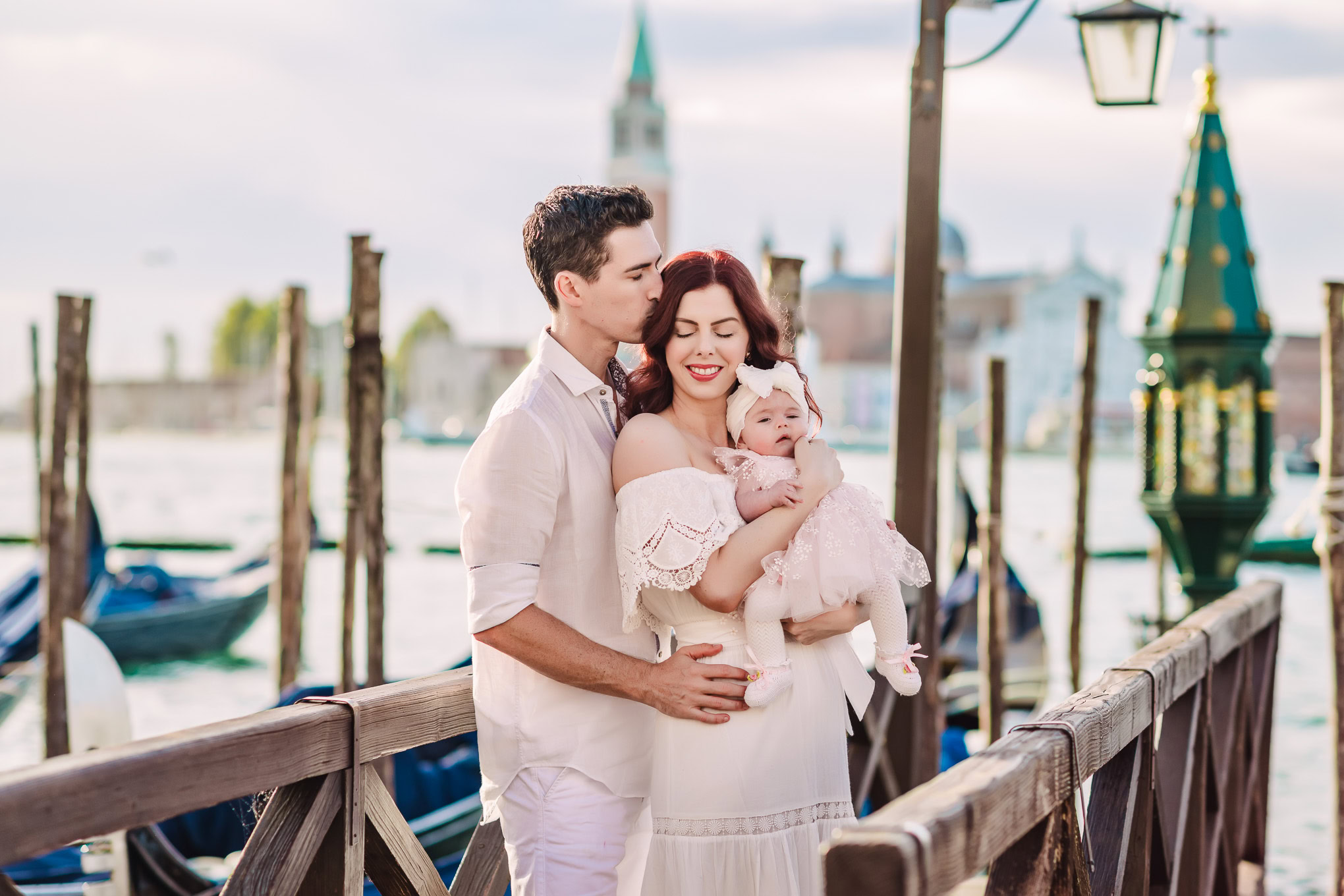 A family sharing a tender moment on a Venice dock, with soft natural light illuminating their joyful interaction and sce.
