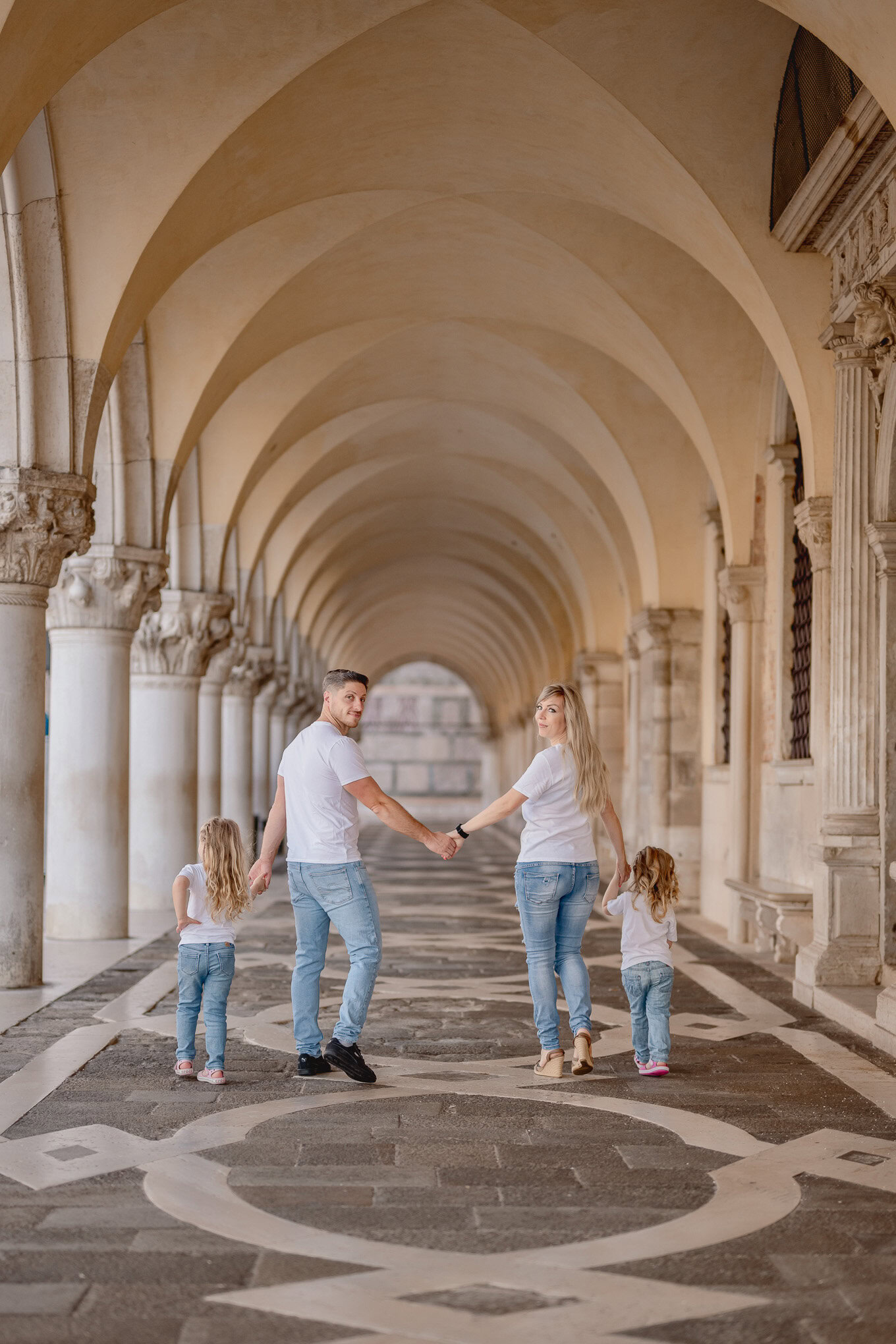 A colorful family walks hand-in-hand through a historic Venetian arcade, enjoying the warm sunlight and architectural be.