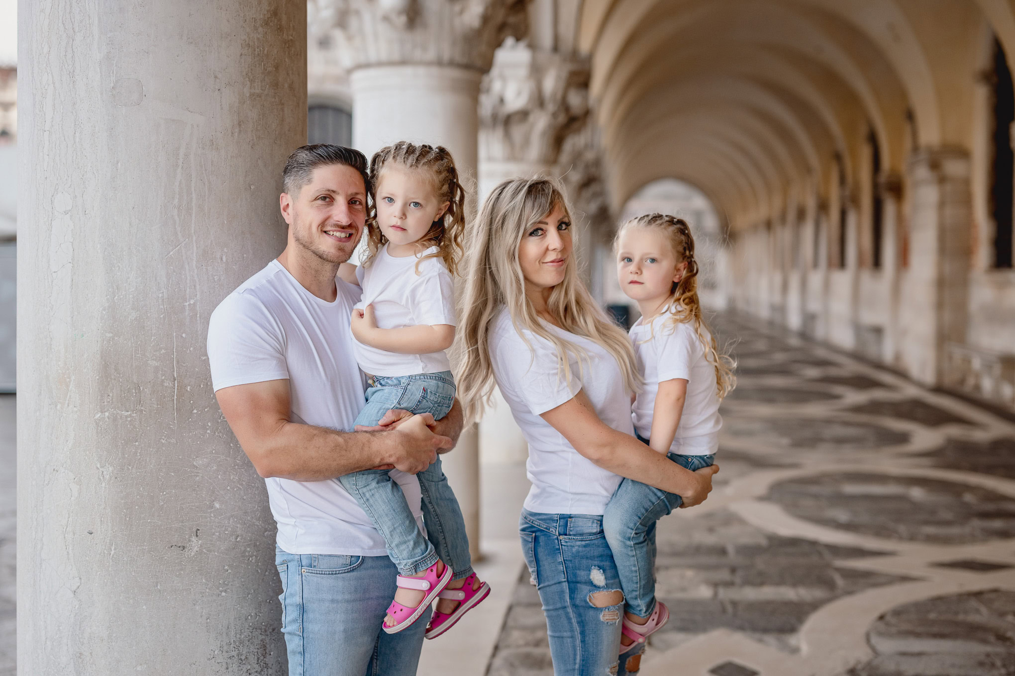 Family of four enjoying a walk along Venetian arches with historic architecture in the background.