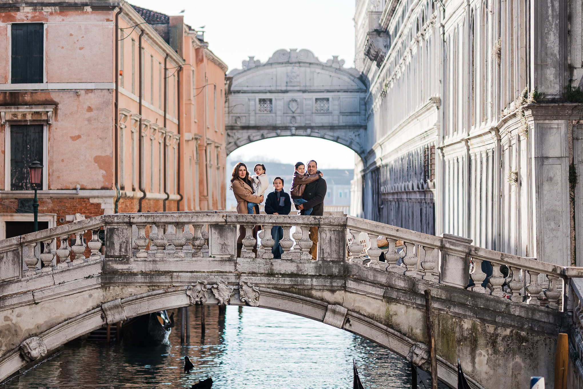 Group of people on a Venetian bridge with historic buildings and canal in the background.