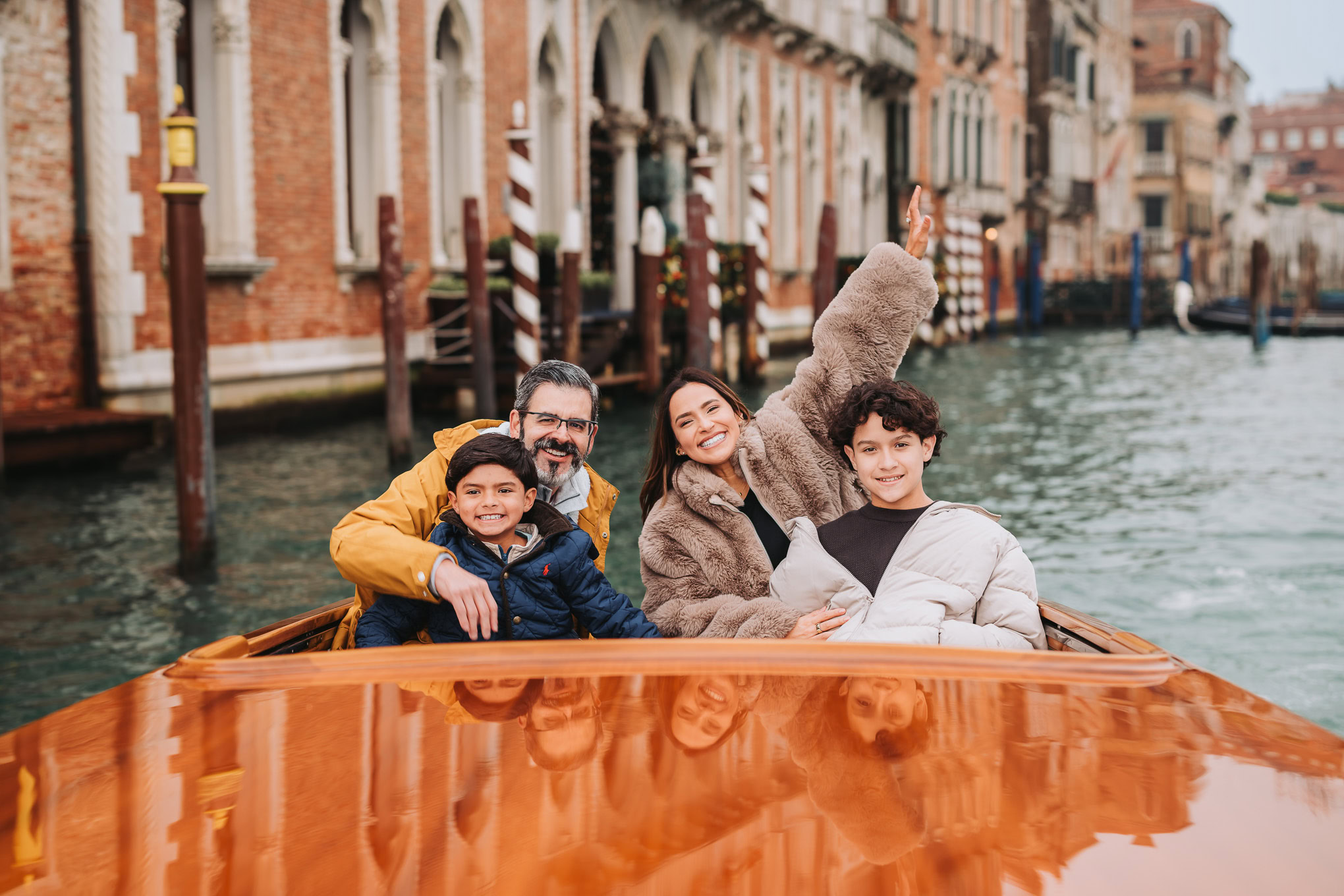 Enjoying a family boat ride along Venice canals, with sunlight illuminating historic buildings and joyful interactions.