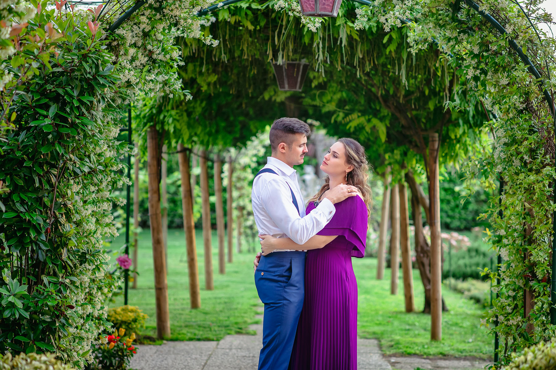 Couple embracing under greenery arch in Venice, soft light, romantic mood, peaceful moment.