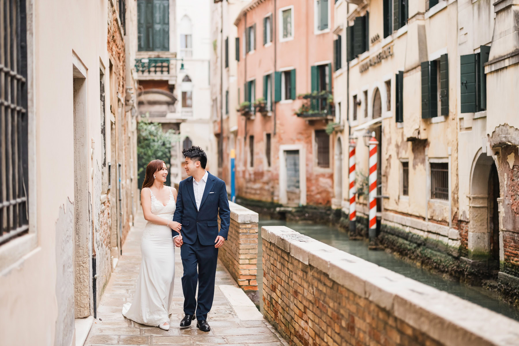 Couple walking along a Venice canal at sunset, romantic and calm atmosphere.