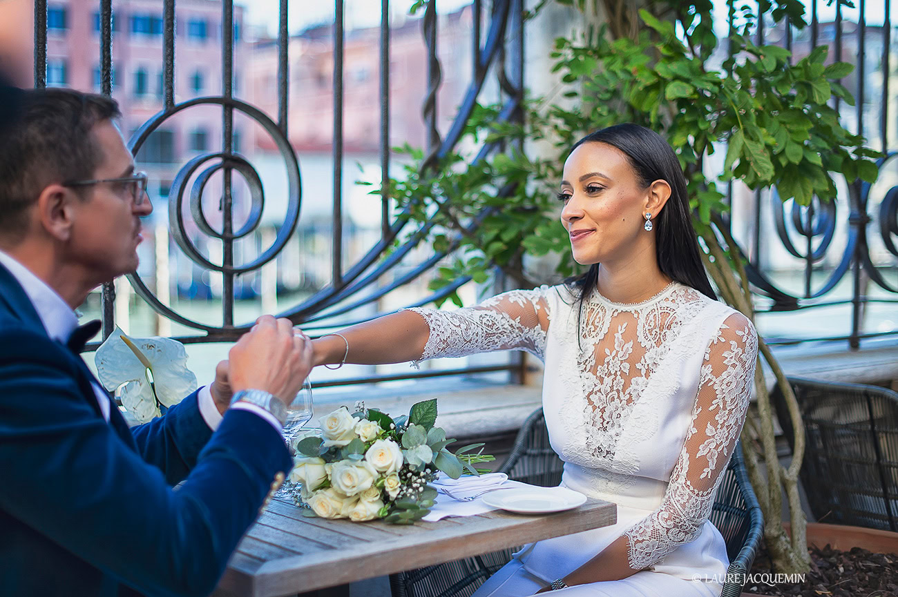A couple enjoying a romantic moment on a Venice terrace with soft light and lush greenery.