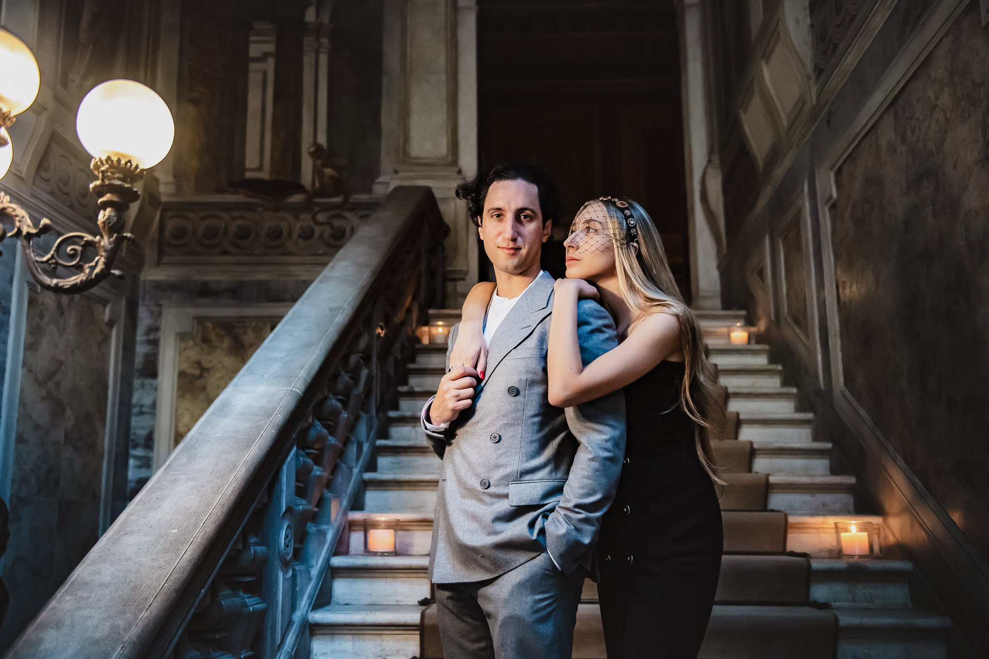 A couple standing on a grand staircase in Venice, bathed in warm, romantic lighting, exuding intimacy and elegance.