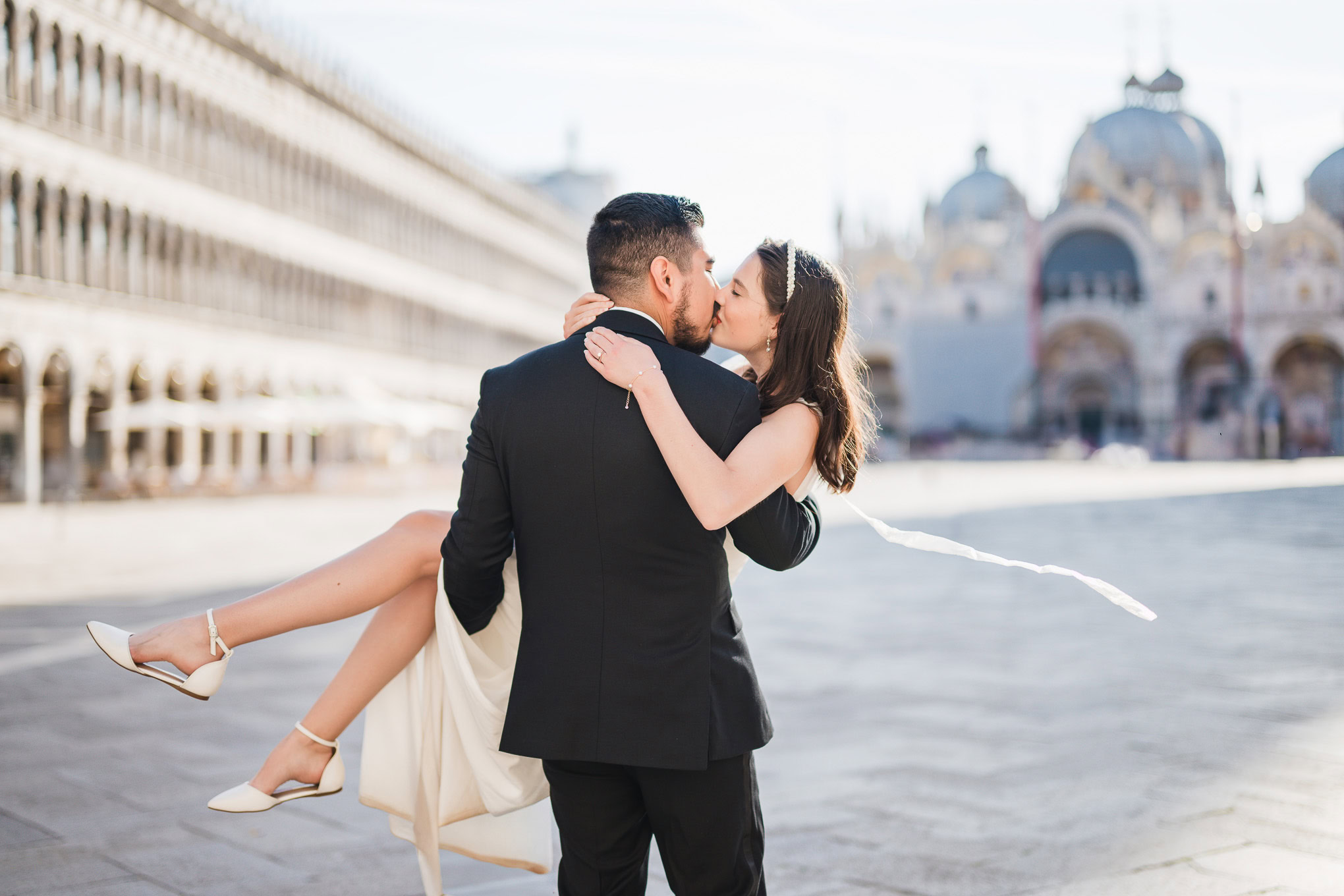 Romantic couple embracing in Venice with soft sunlight, capturing an intimate and dreamy atmosphere.