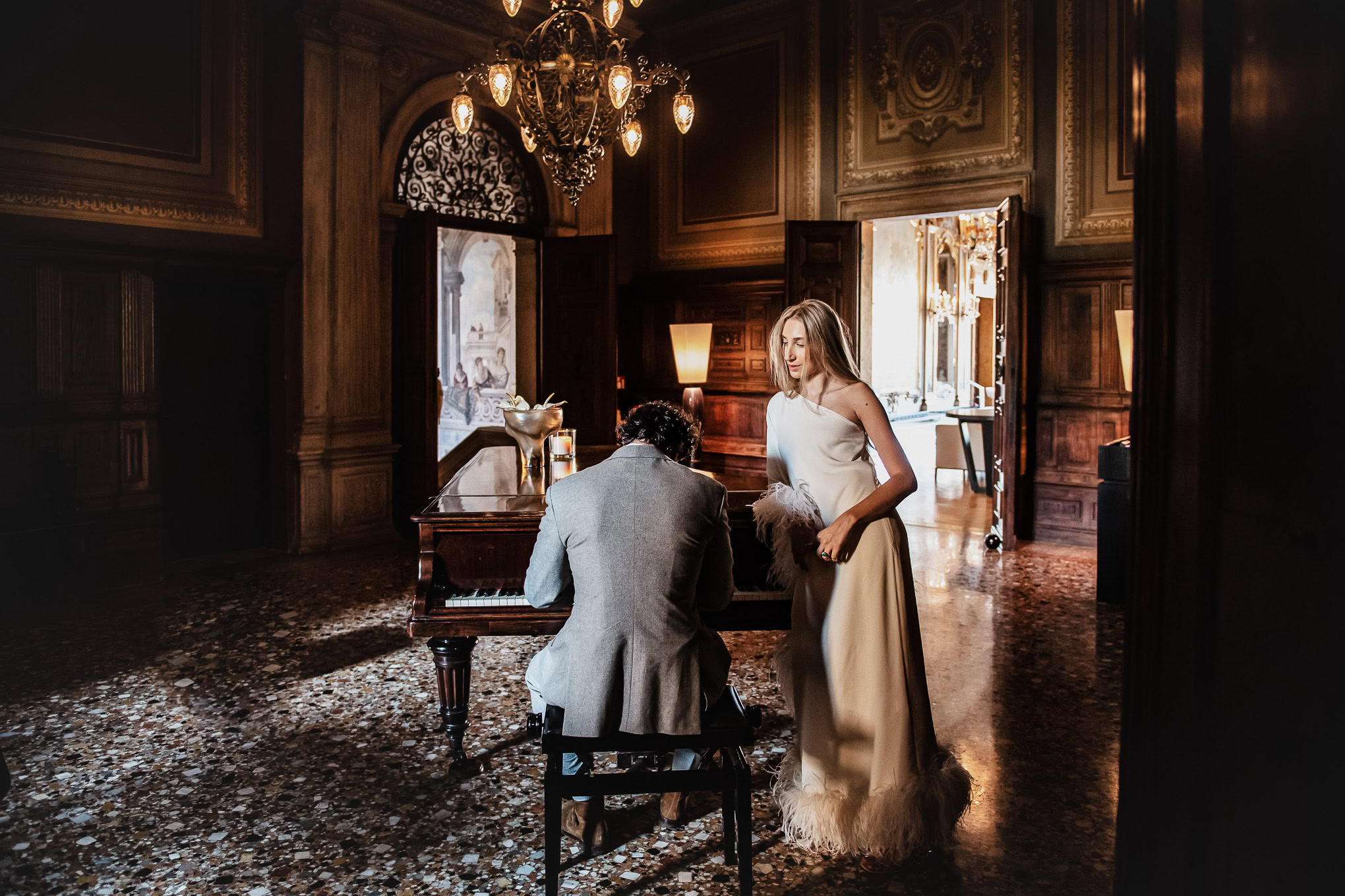 Romantic couple in elegant attire sharing a tender moment in a luxurious, warmly lit Venetian interior.