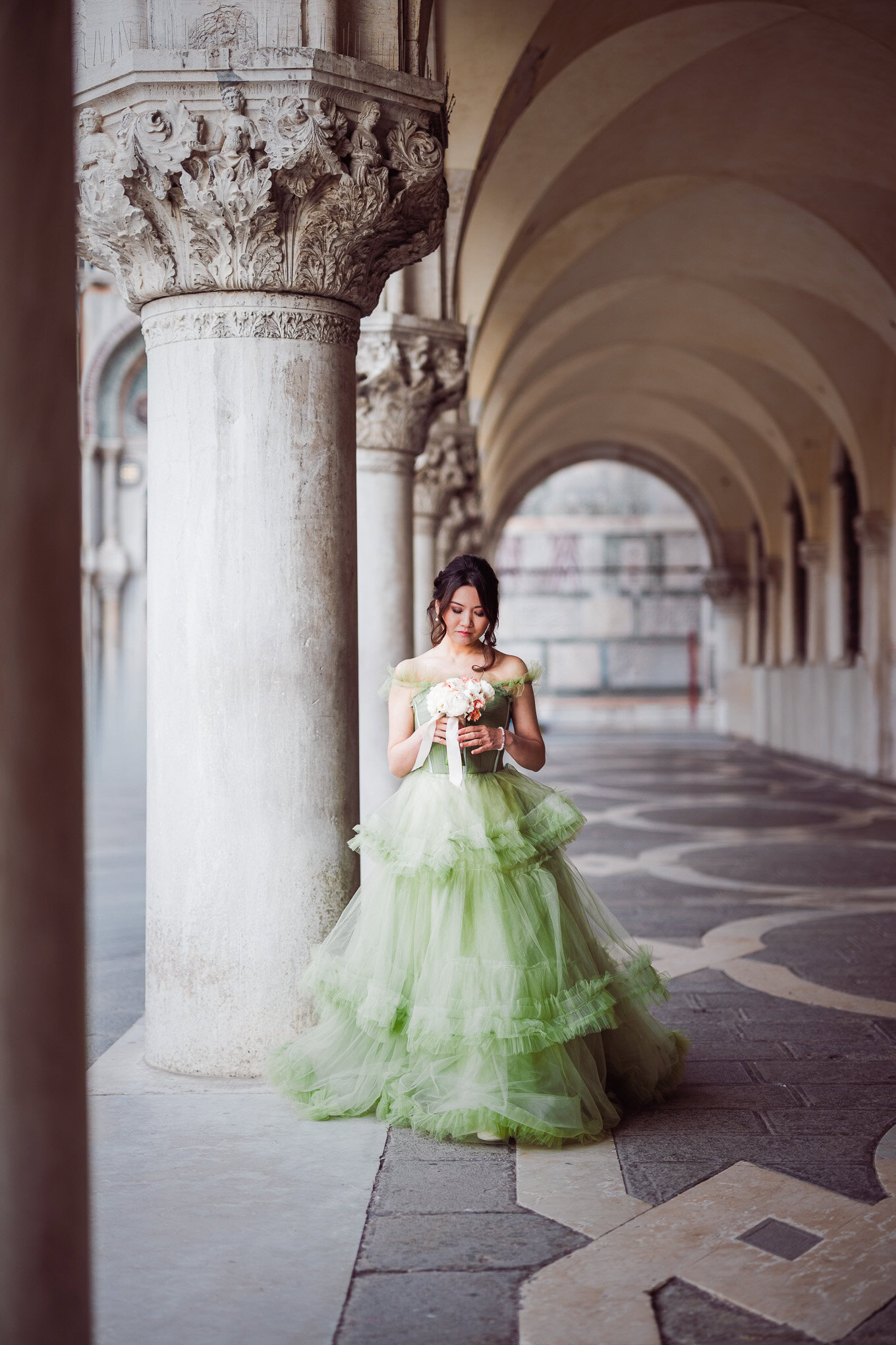 A women in a romantic embrace under Venetian arches, bathed in soft, natural light, capturing an intimate travel moment.