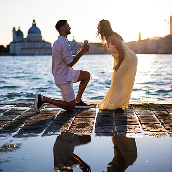 A man proposes to a woman on a Venice waterfront at sunset, capturing a heartfelt moment of love and commitment.