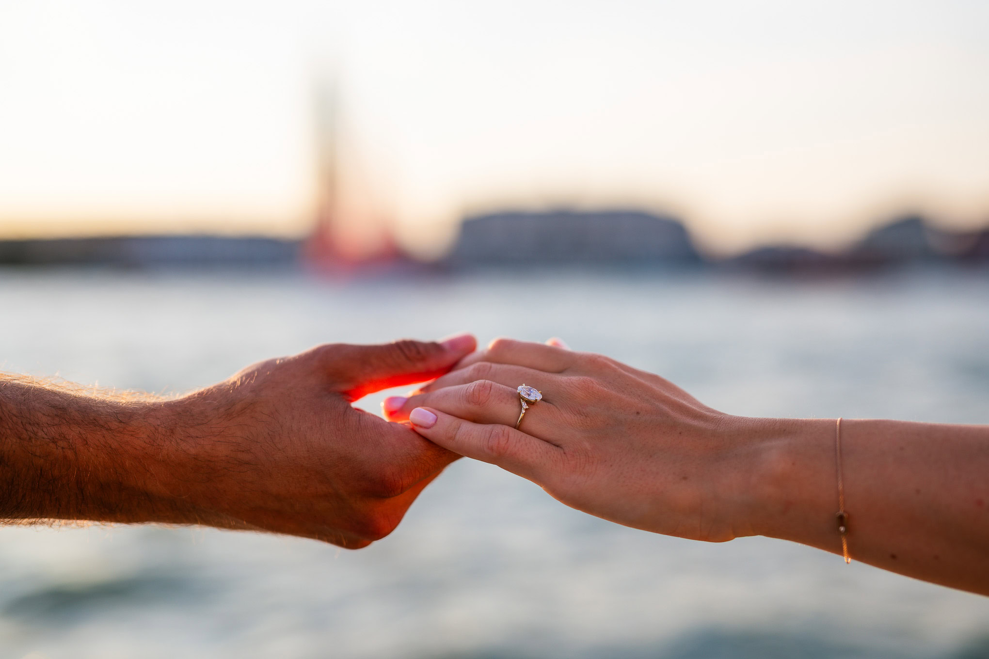An engaged hand reaches out with a sparkling ring, capturing a heartfelt proposal against Venice's scenic backdrop.