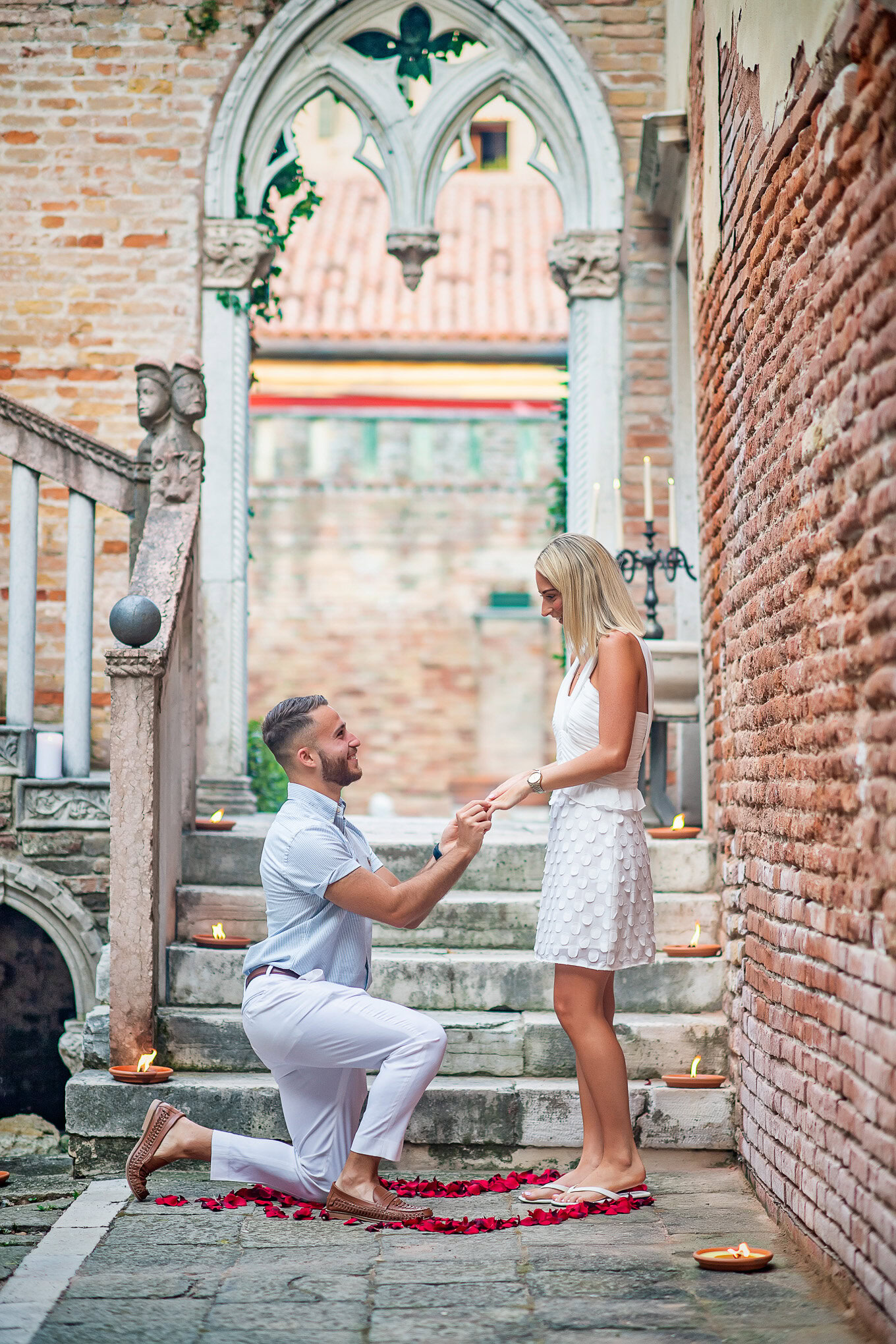 A man proposes to a woman on historic Venetian stairs, capturing a heartfelt moment of love and surprise.