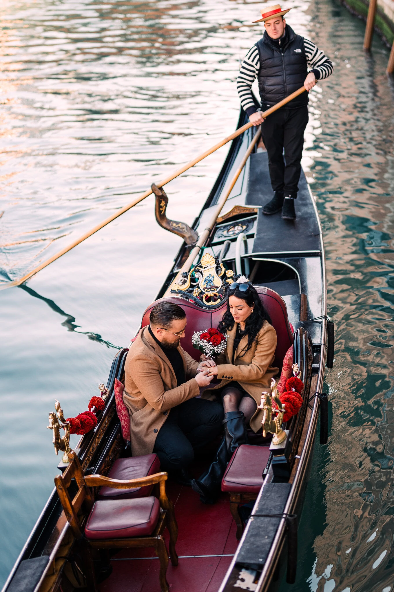 A man proposes to a woman on a gondola in Venice, capturing a heartfelt moment of love and surprise.