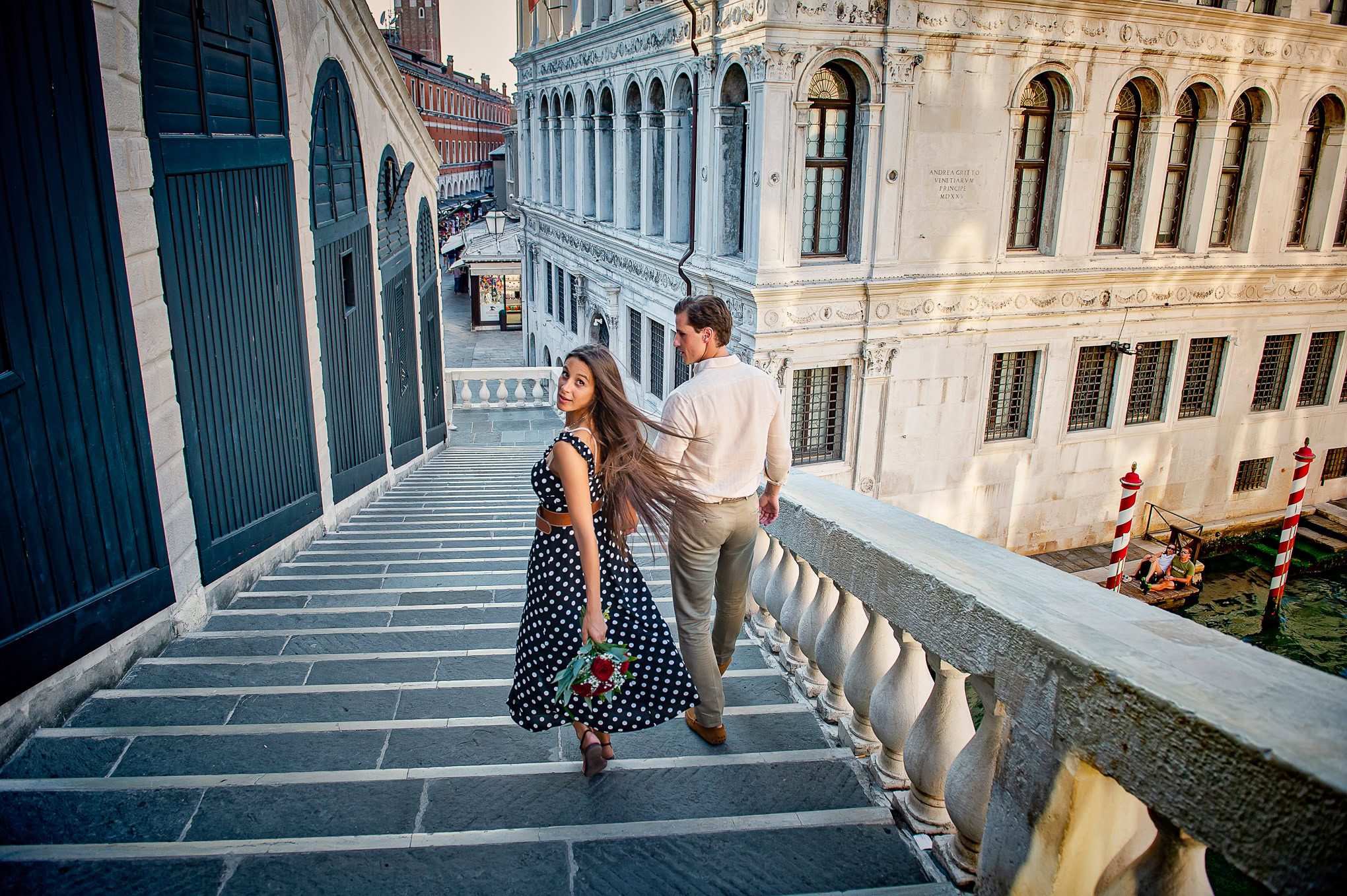 Venetian scene with a couple walking down historic stairs in a romantic city setting.