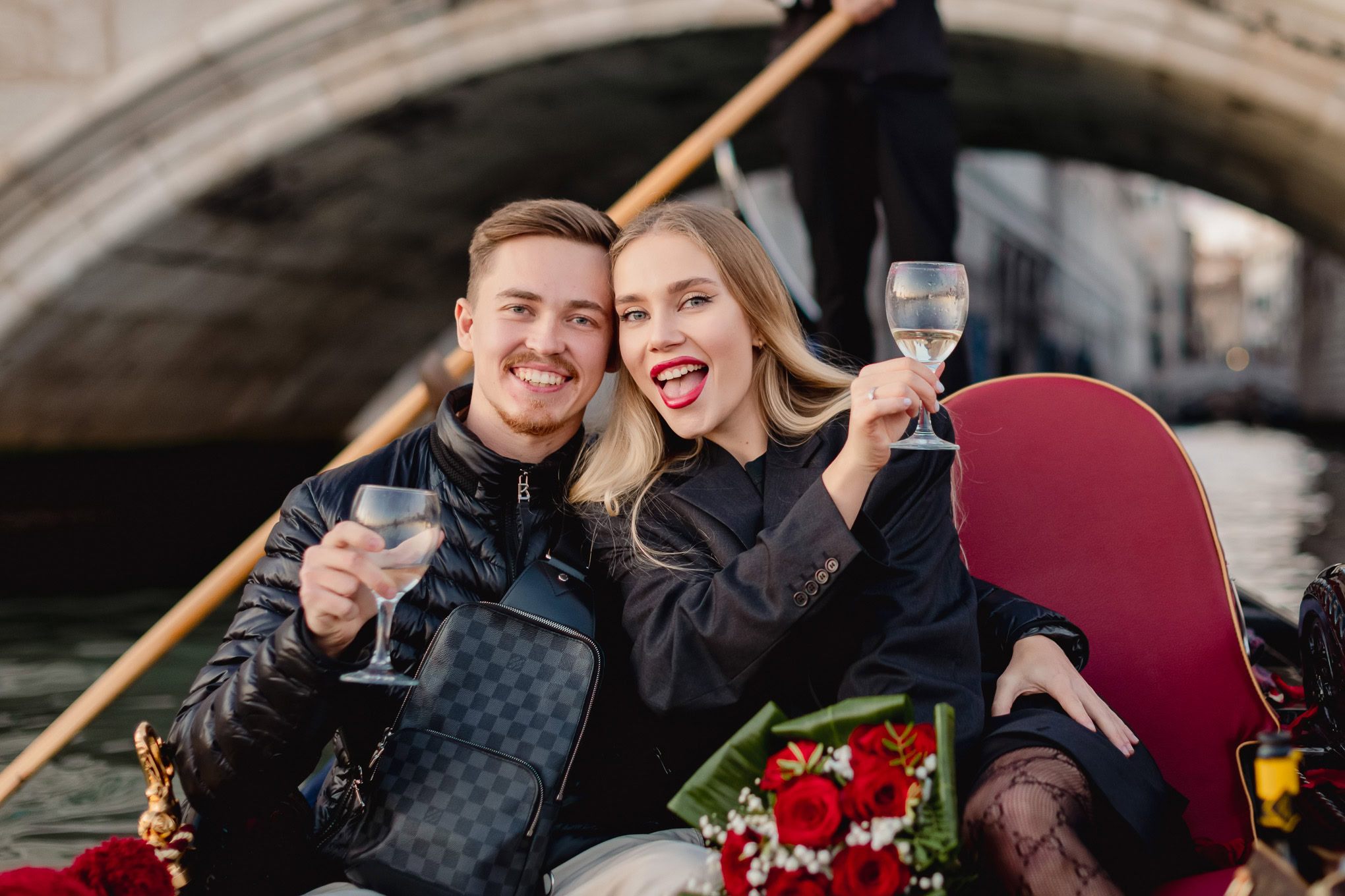 A woman excitedly accepts a marriage proposal from her partner on a gondola in Venice, capturing a joyful and emotional.