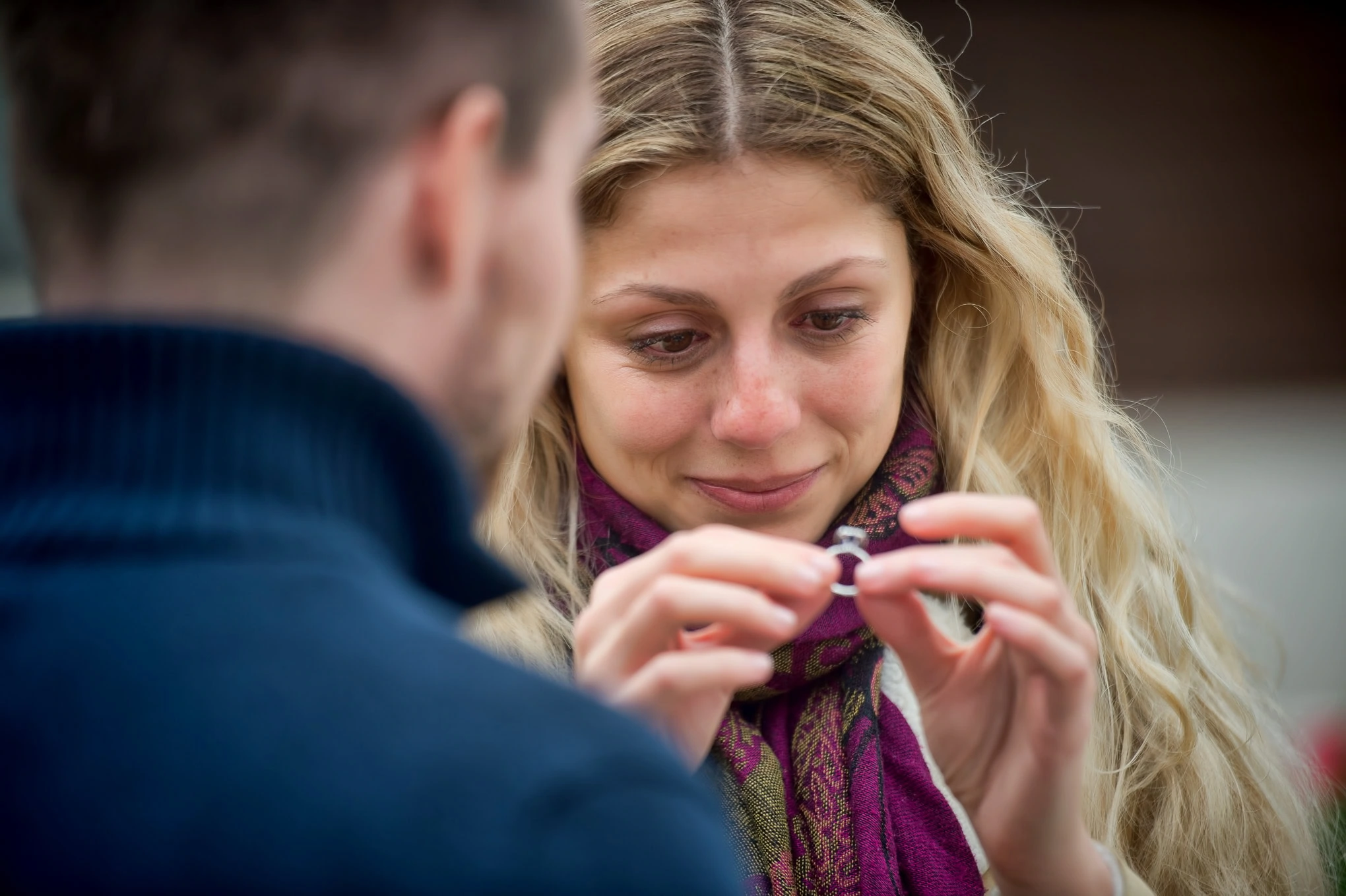 A woman excitedly accepts a ring from her partner during a romantic proposal in Venice.