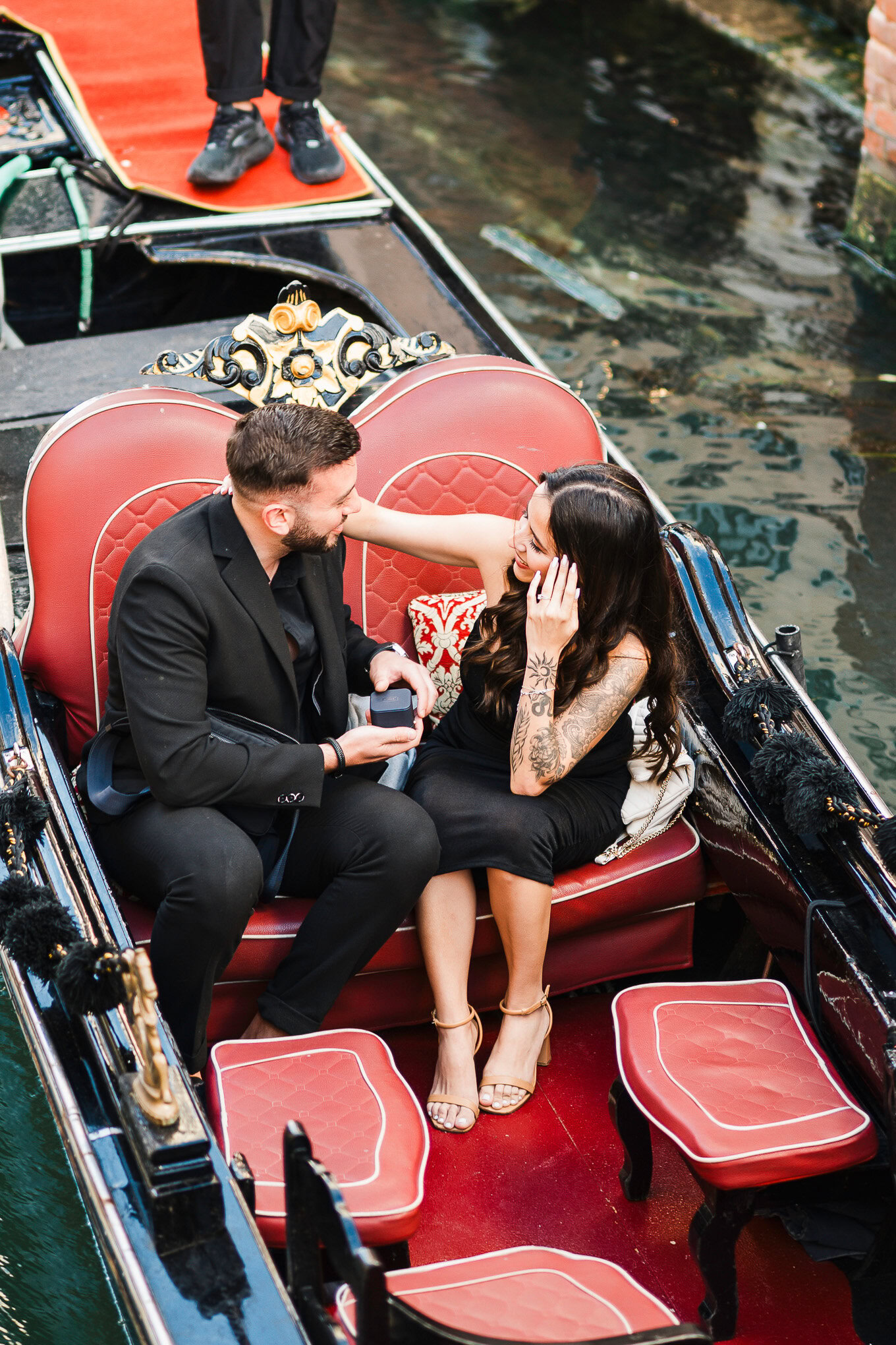 A man proposes to a woman on a gondola in Venice, capturing a heartfelt moment of love and surprise.