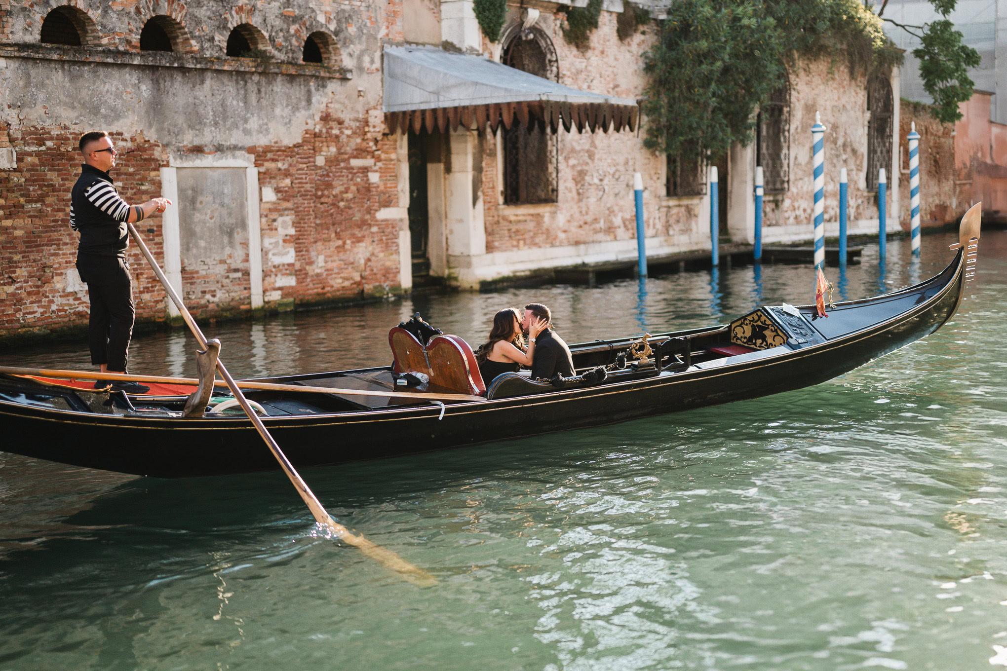 A couple shares a romantic moment as one proposes on a gondola in Venice, capturing a heartfelt and emotional scene.