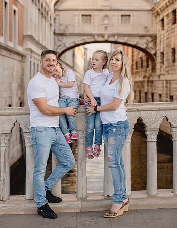 Family standing on a bridge in San Marco Square, Venice, with historic buildings in the background.