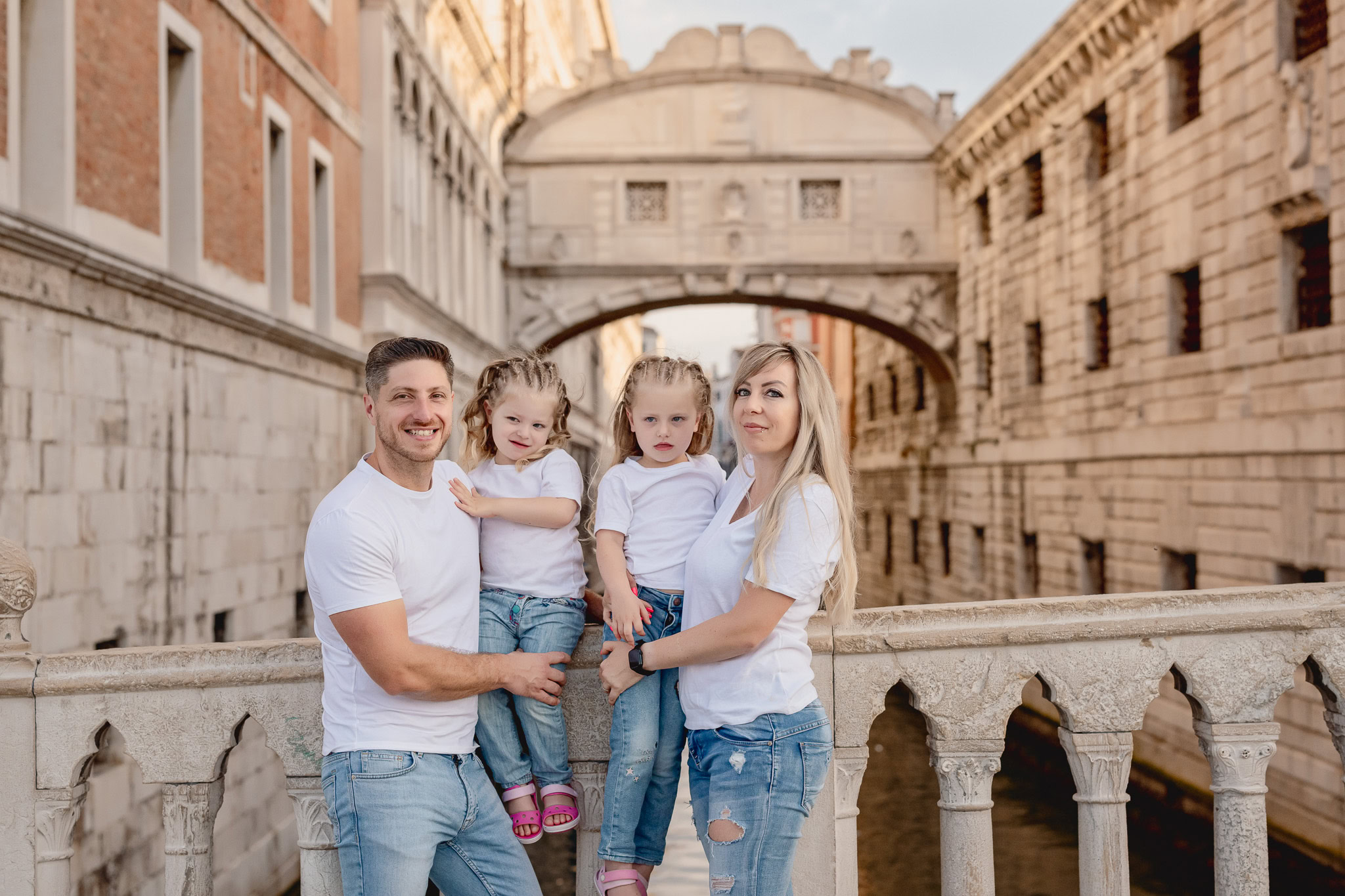 Family standing on a bridge in San Marco Square with historic buildings in the background.