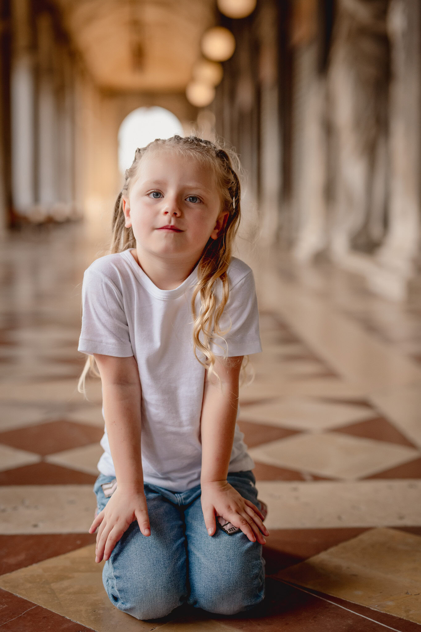 A girl sitting on the floor in a corridor with arches and warm lighting at San Marco Square.