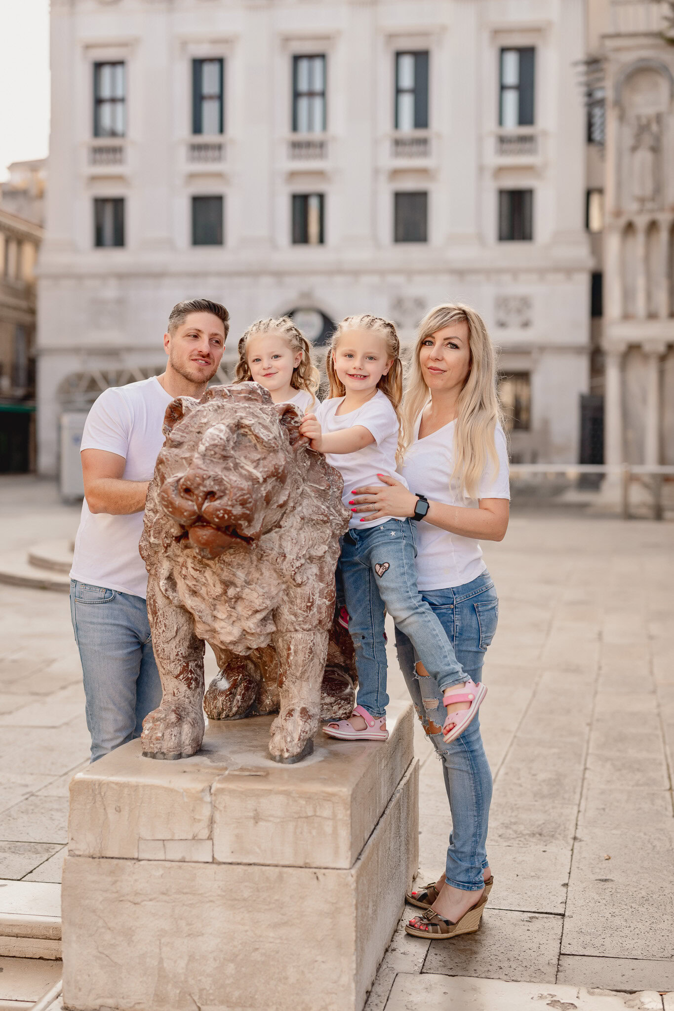 Family with two children and a dog standing on a stone pedestal in San Marco Square, Venice.