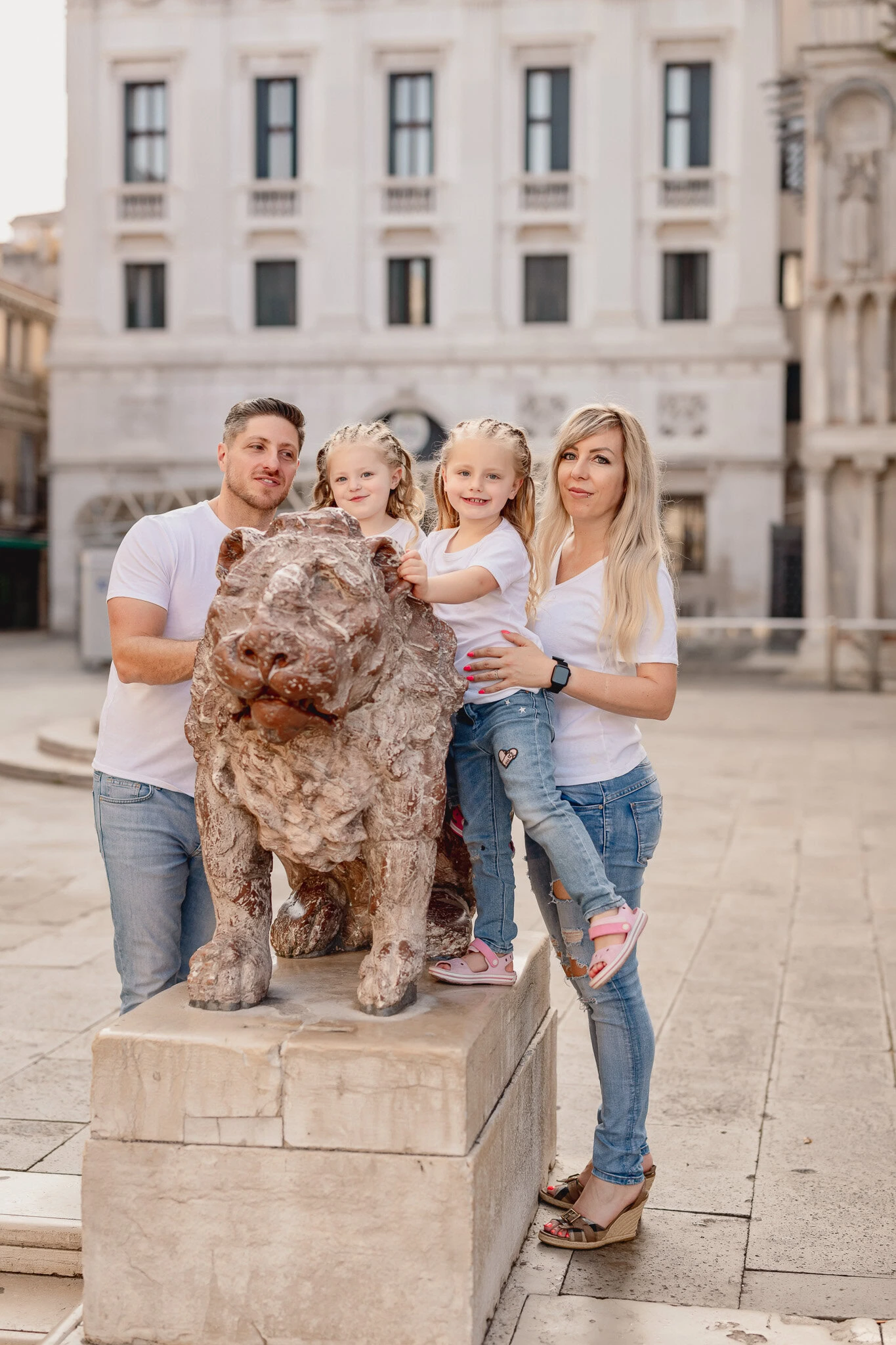 Family with two children and a dog standing on a stone pedestal in San Marco Square, Venice.