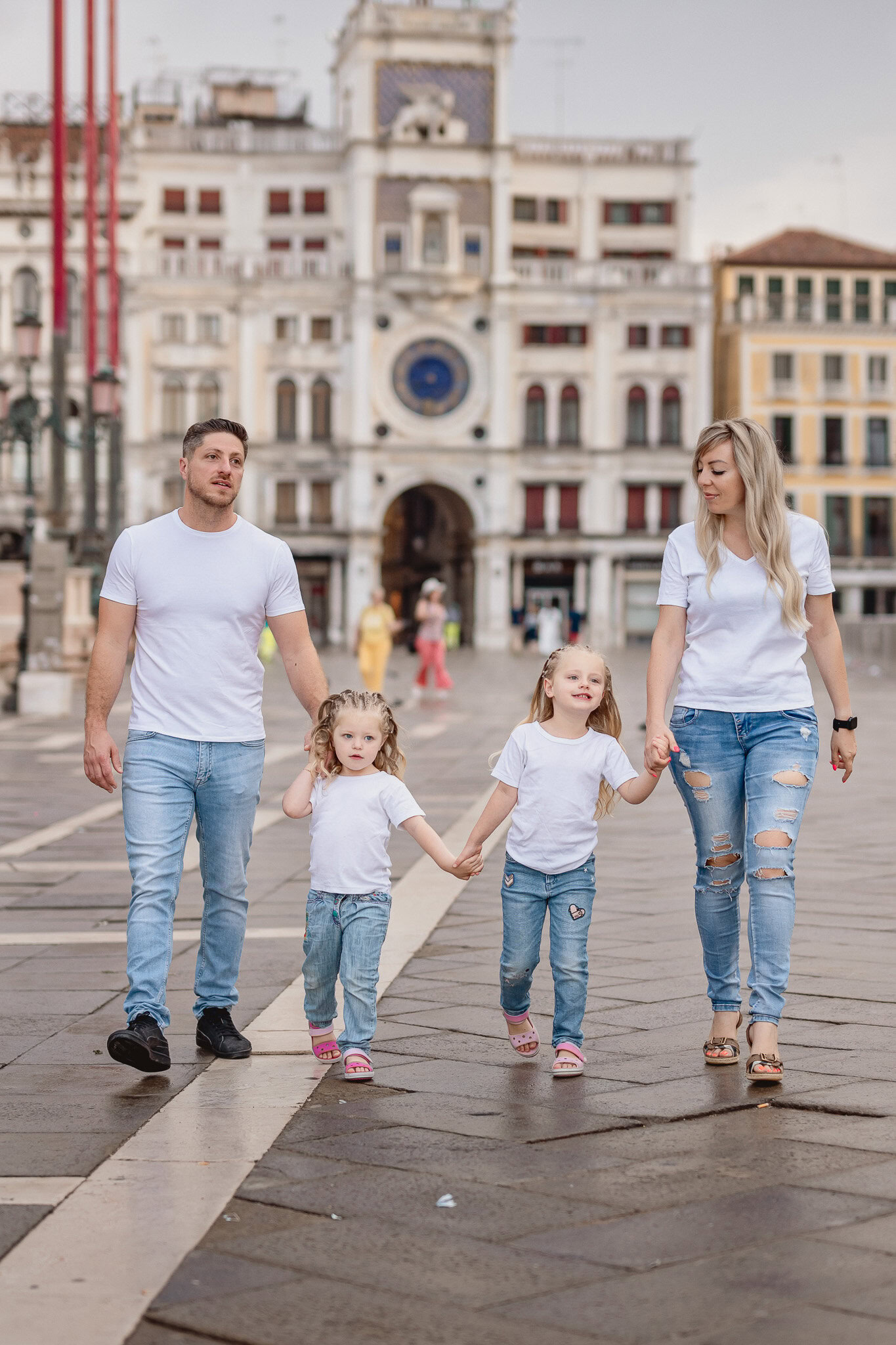 A family walking together in San Marco Square, Venice, with historic buildings in the background.