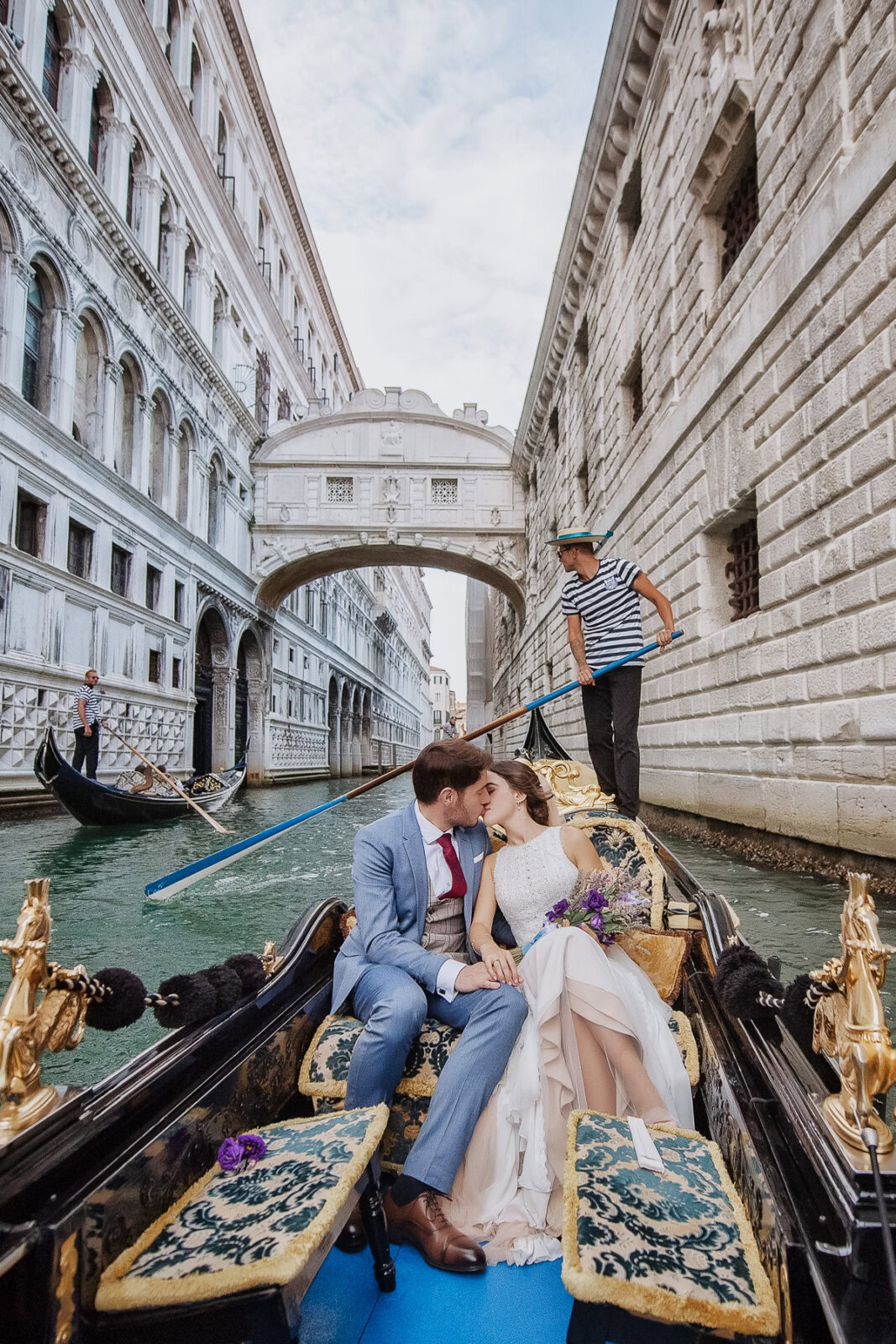 Couple sharing a symbolic, intimate gondola moment in Venice with water reflections and historic arc.