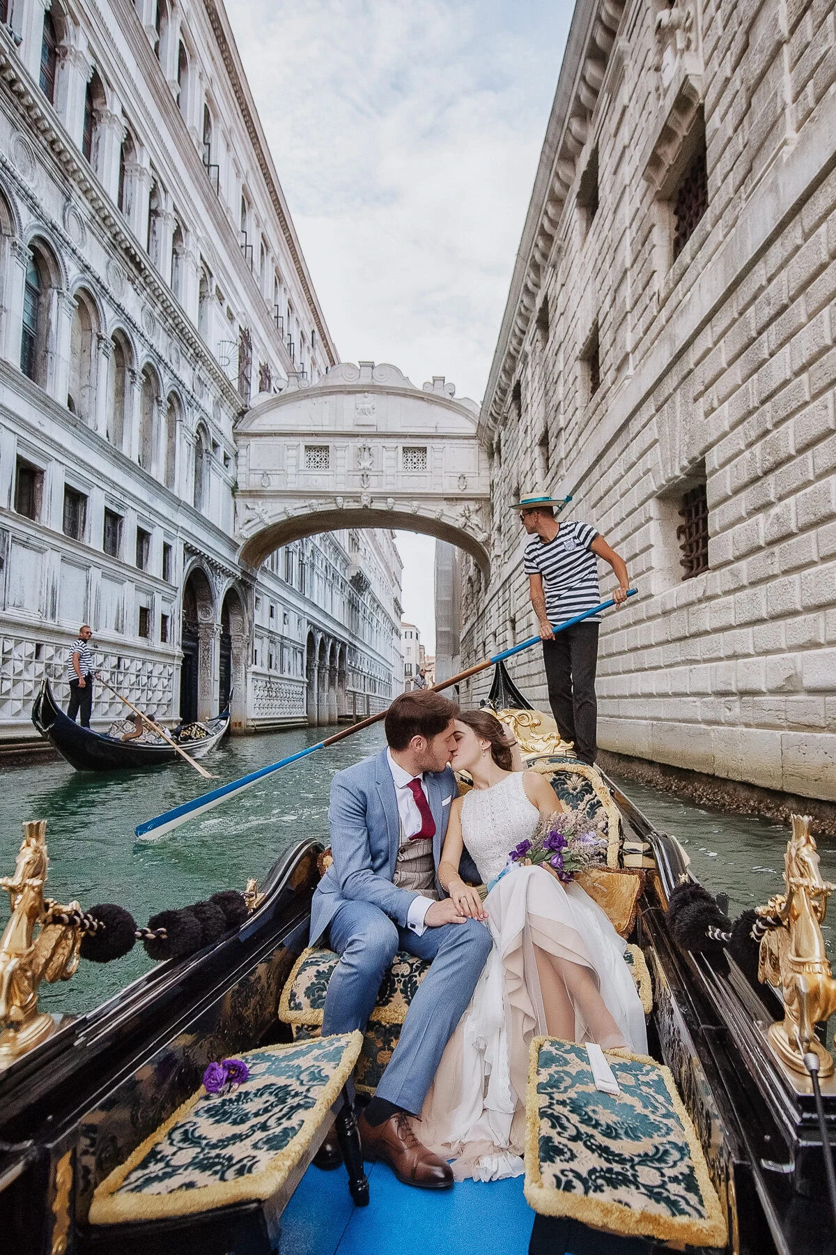 Couple sharing a symbolic, intimate gondola moment in Venice with water reflections and historic arc.