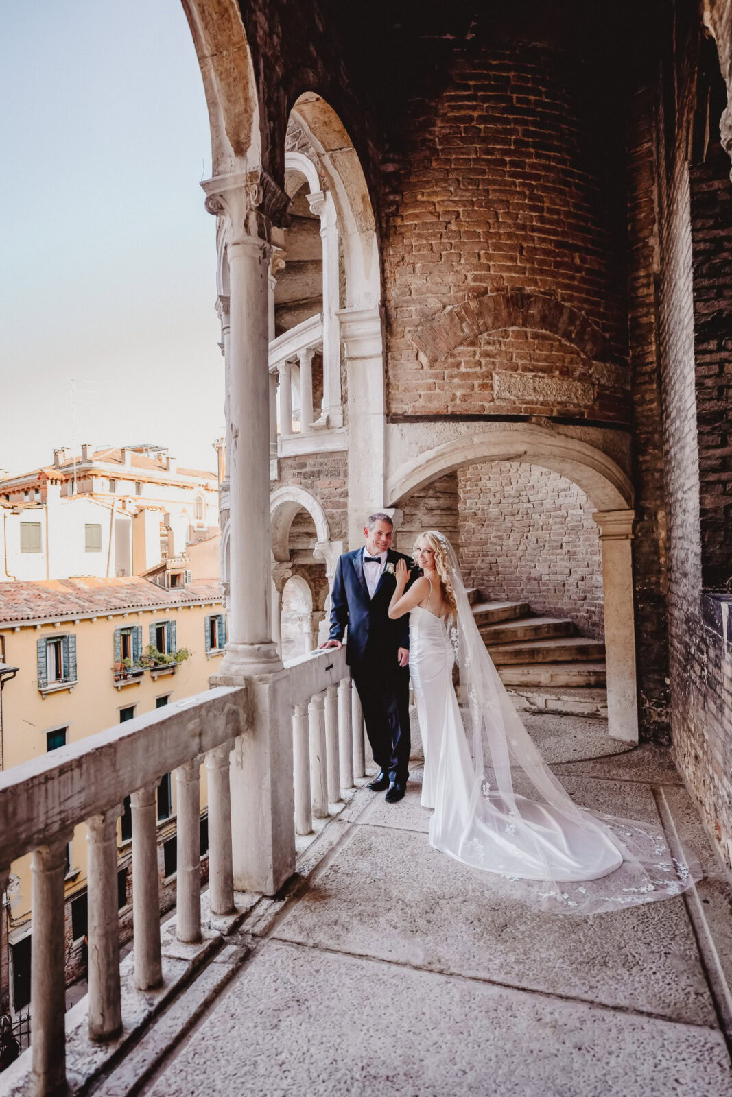 Couple in elegant wedding attire outdoors at scala del bovolo
