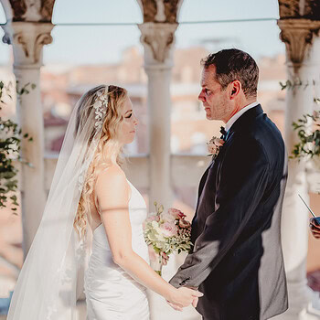 Romantic couple holding hands during a wedding ceremony outdoors.