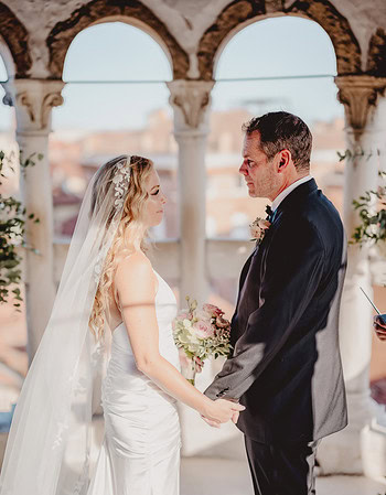 Romantic couple holding hands during a wedding ceremony outdoors.
